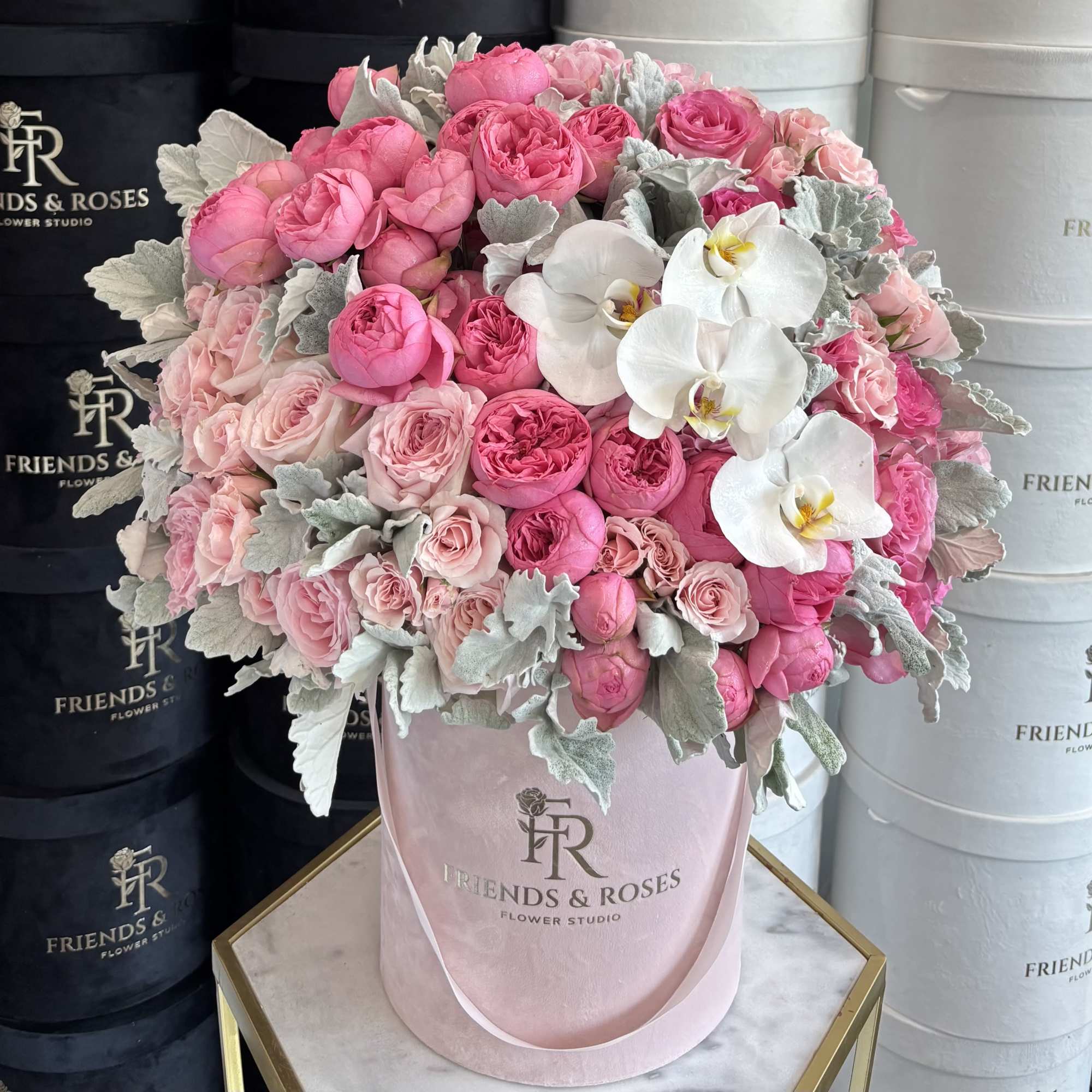 Pink roses and white orchids arranged in a blush hatbox