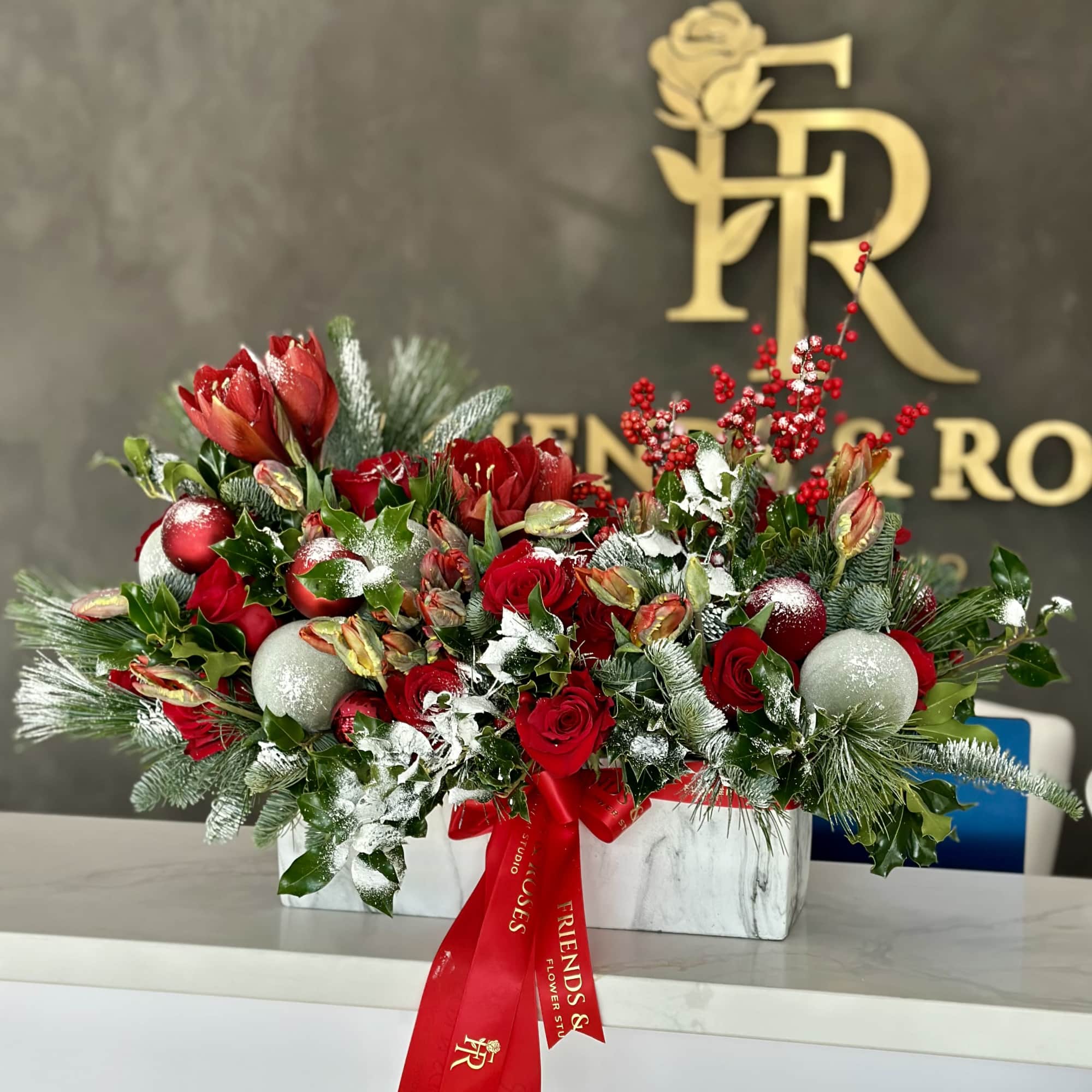 Red floral arrangement with ornaments in a white rectangular vase