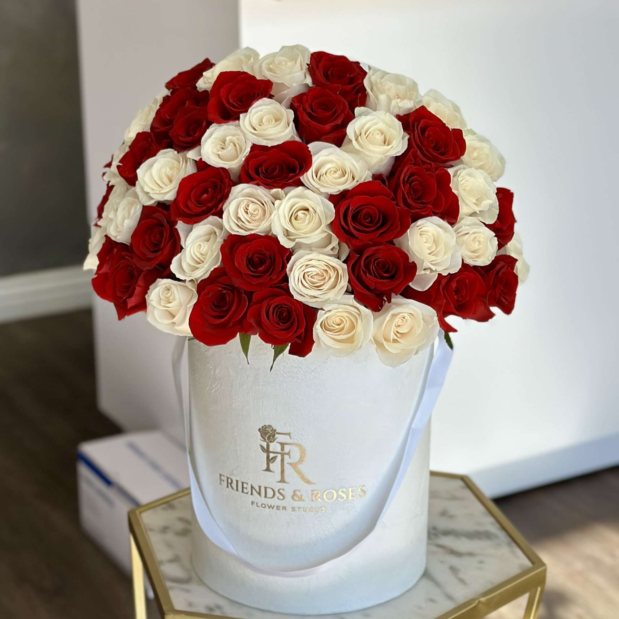 Red and white roses arranged in a white hatbox