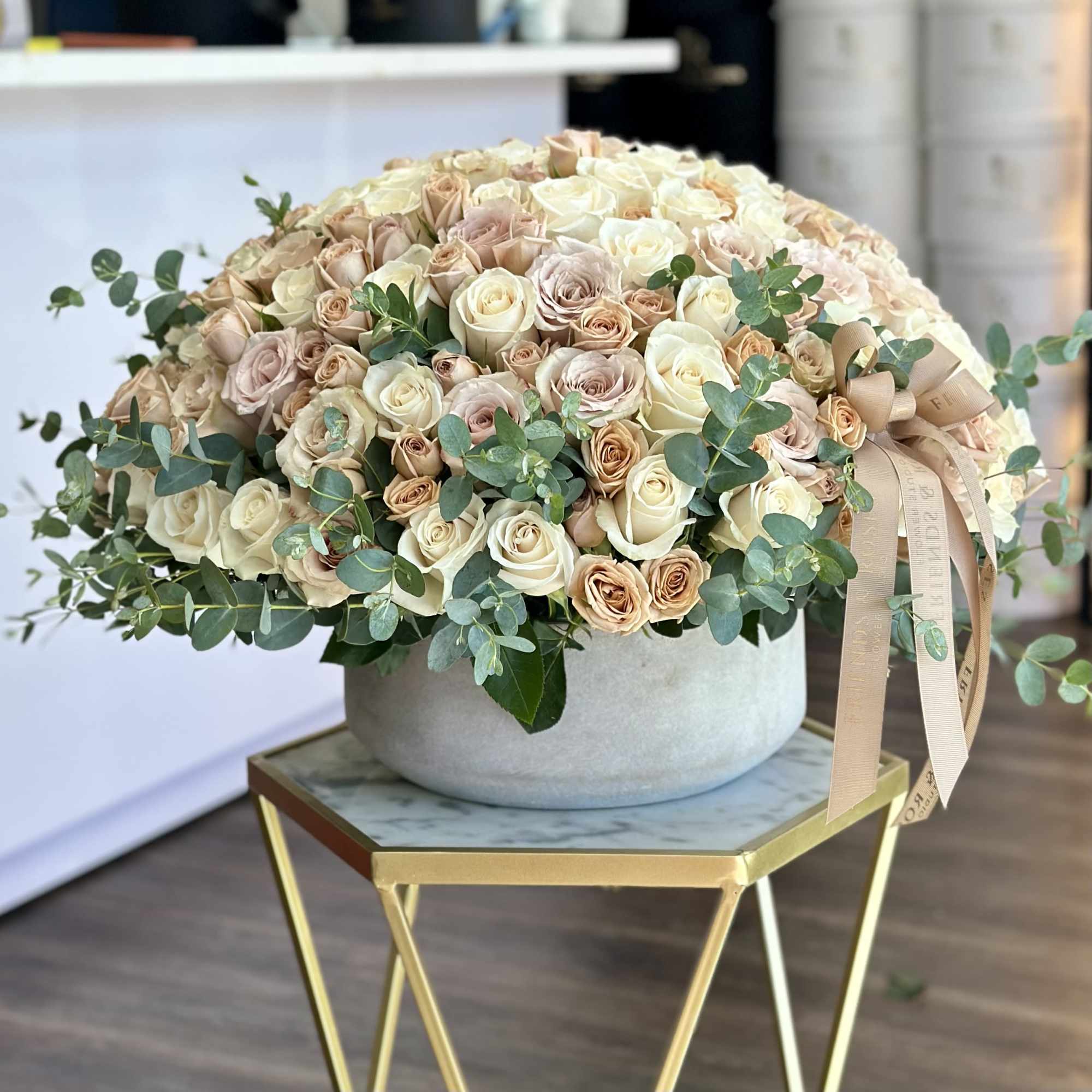 Large bouquet of cream and blush roses in a round vase with eucalyptus