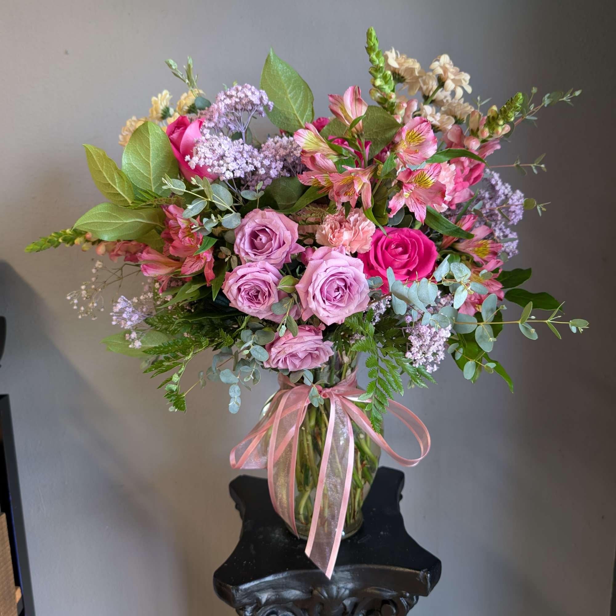 Pink and lavender bouquet in a glass vase with a pink ribbon