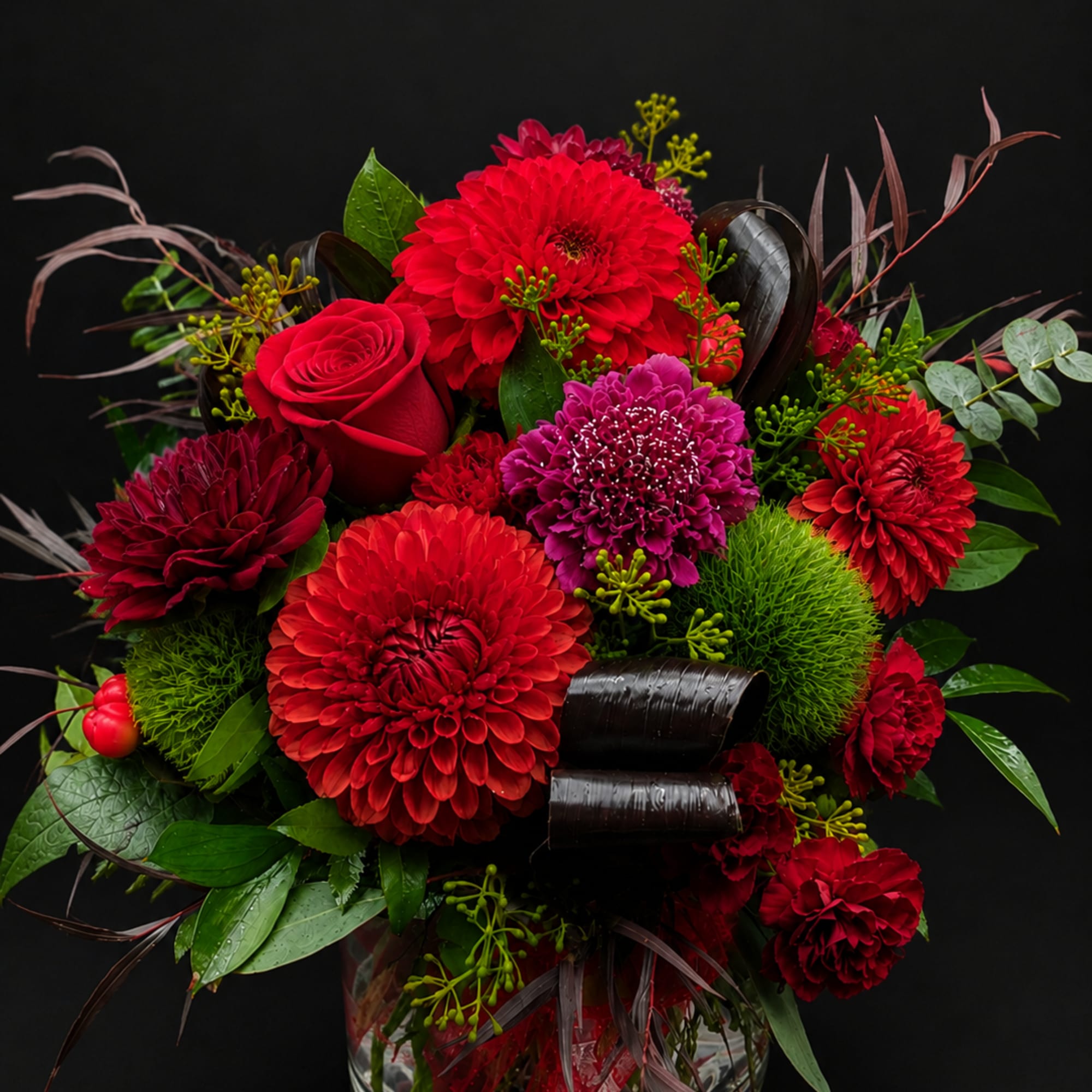 Red and purple flower arrangement in a clear glass vase