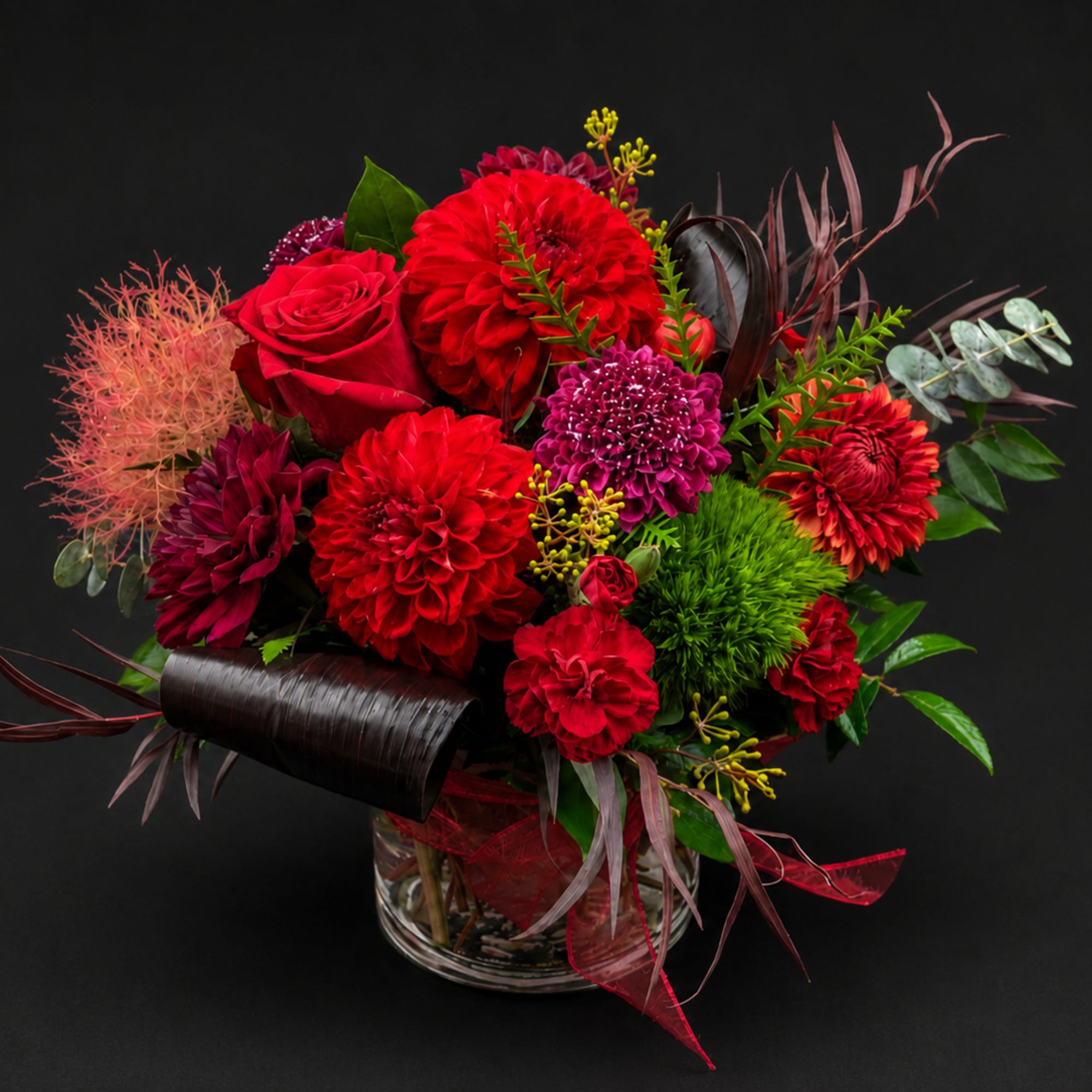 Red and magenta mixed flower arrangement in a clear glass vase
