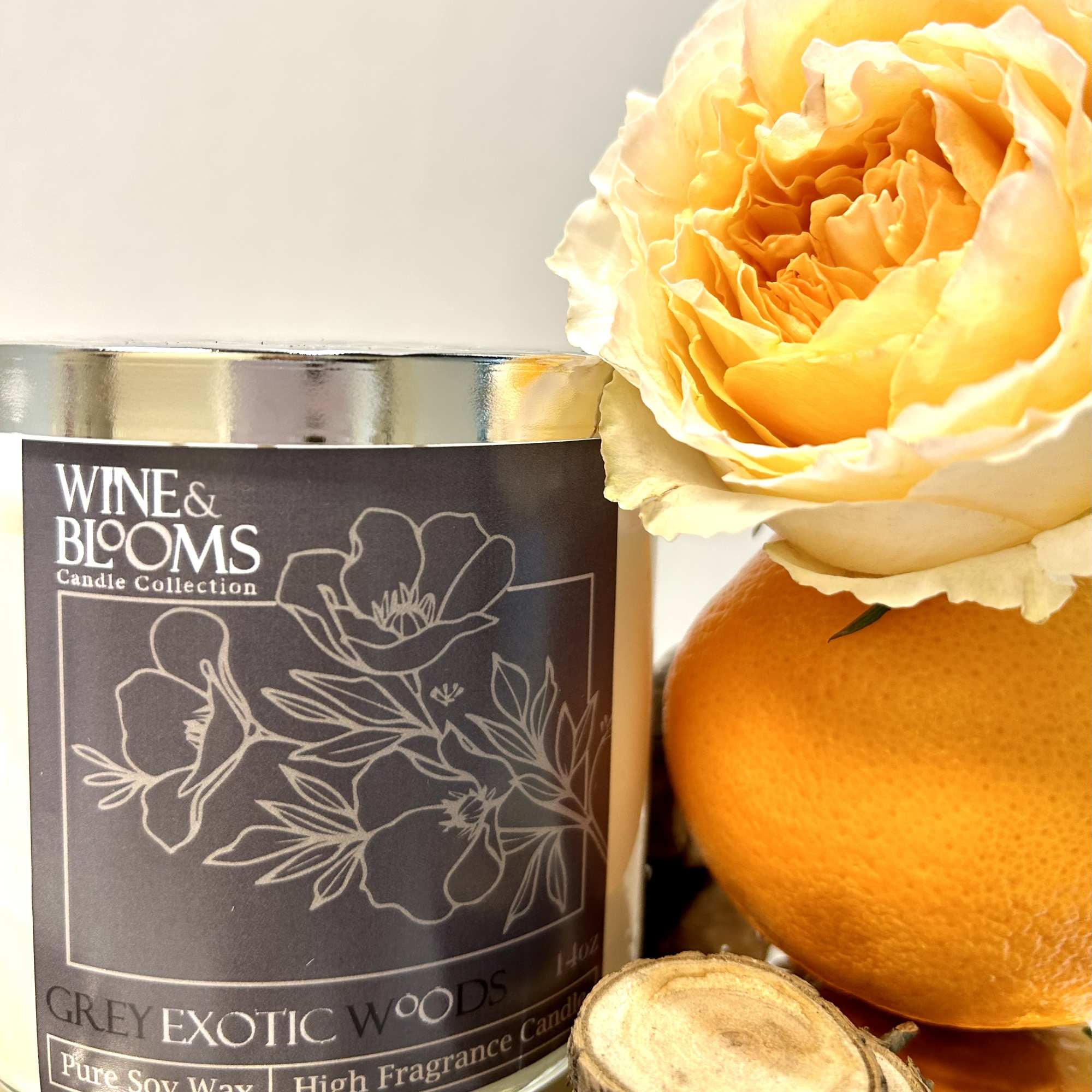 Yellow rose beside a scented candle and orange fruit
