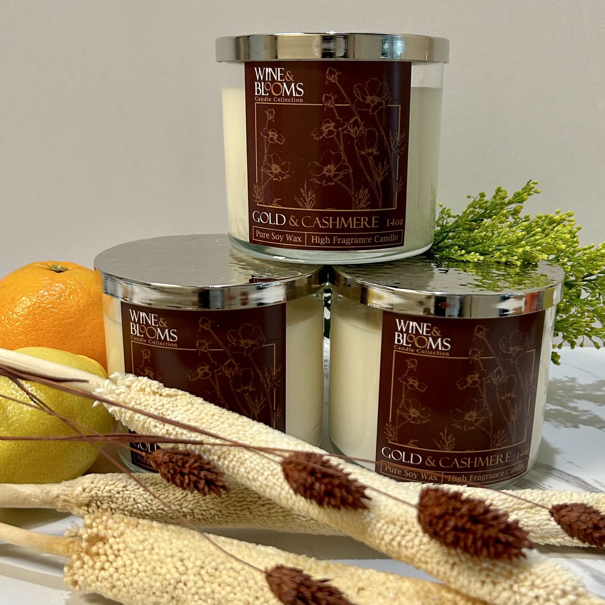 Three scented candles with citrus and dried floral accents
