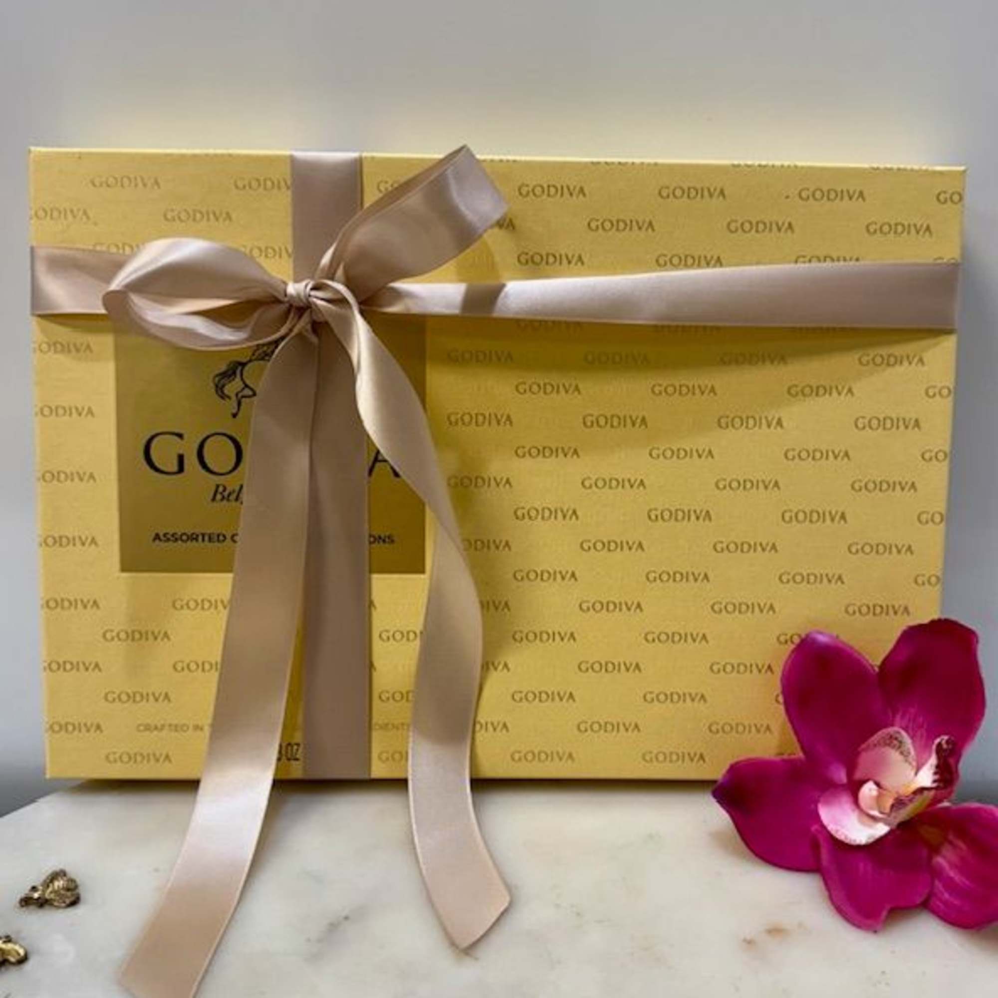 Gift box of Godiva chocolates tied with a satin ribbon and orchid bloom