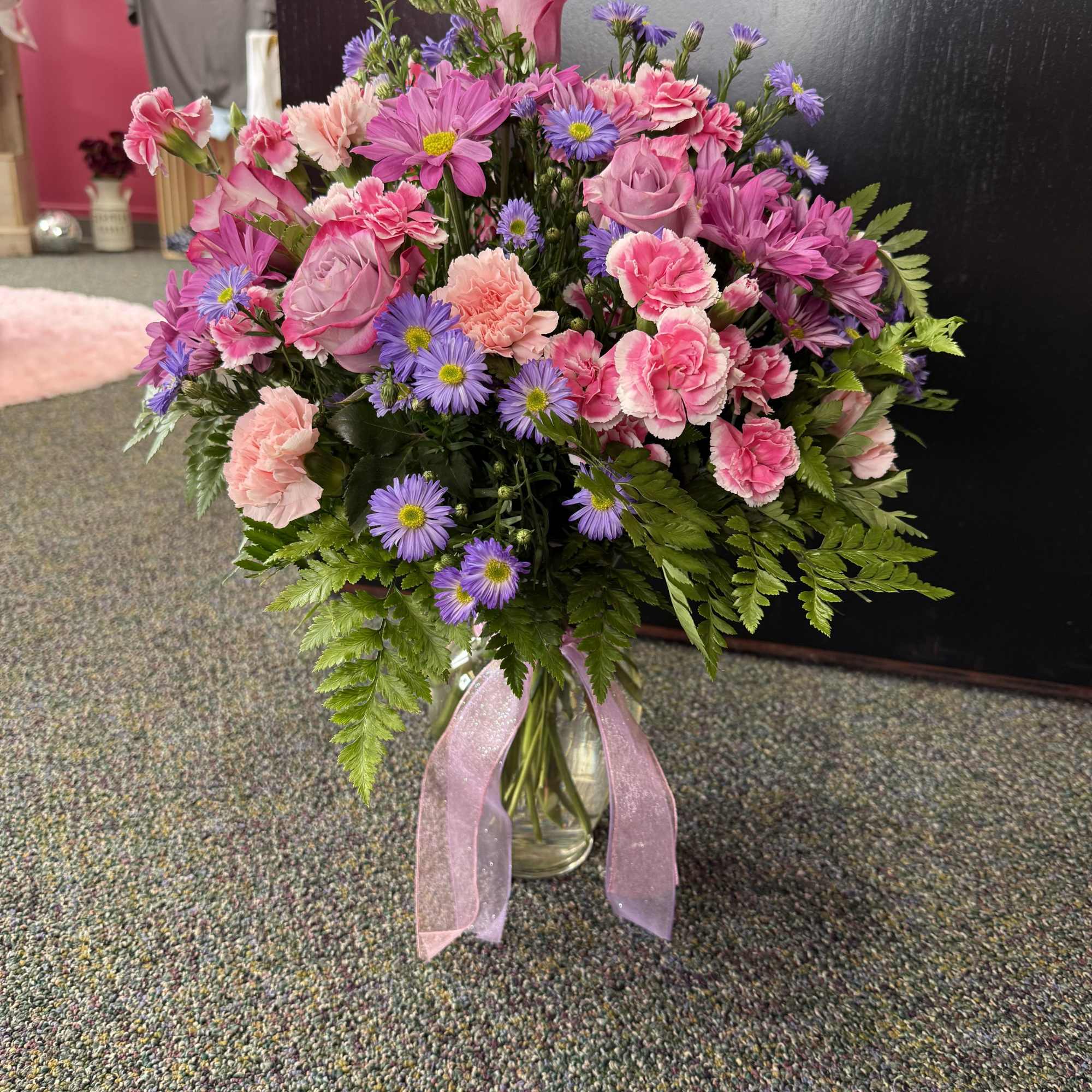 Pink and purple mixed bouquet in a glass vase with a pink ribbon