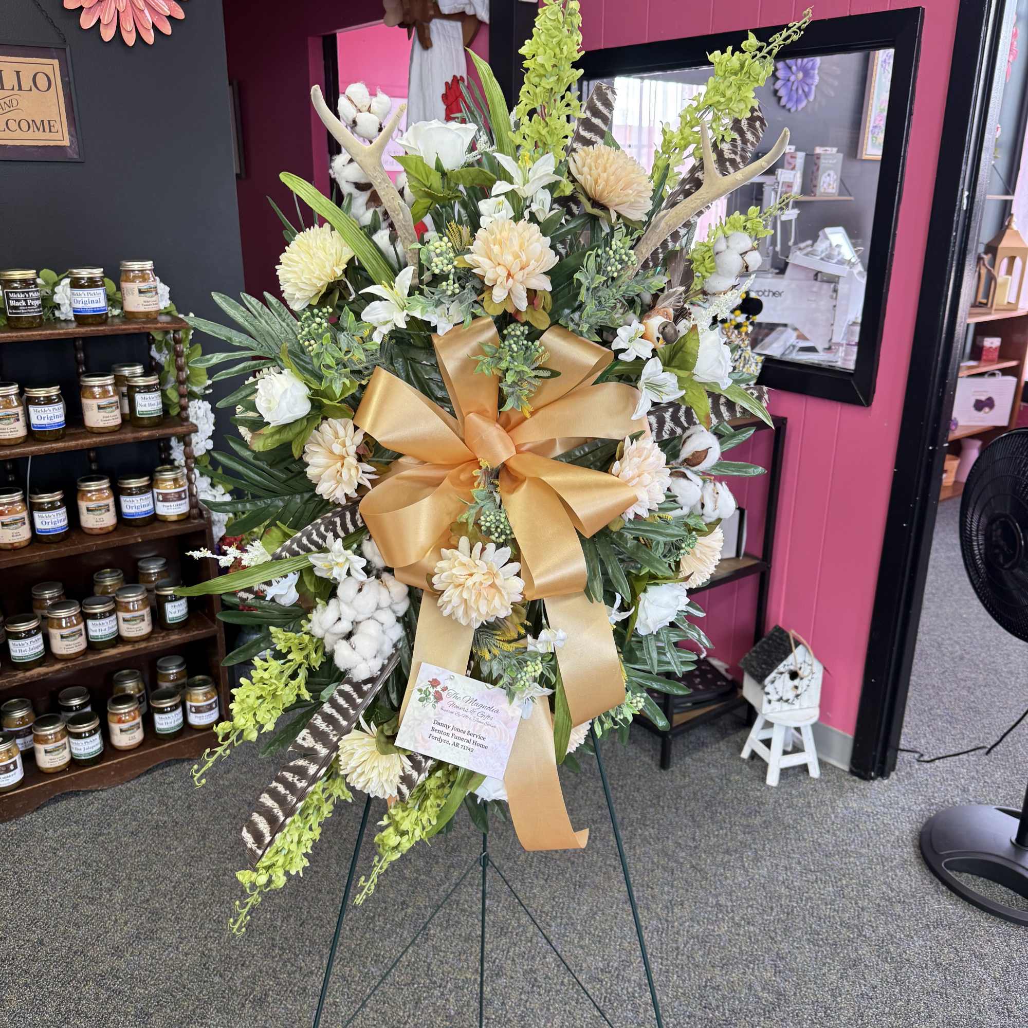 Tall standing floral spray with white and cream blooms and a gold ribbon
