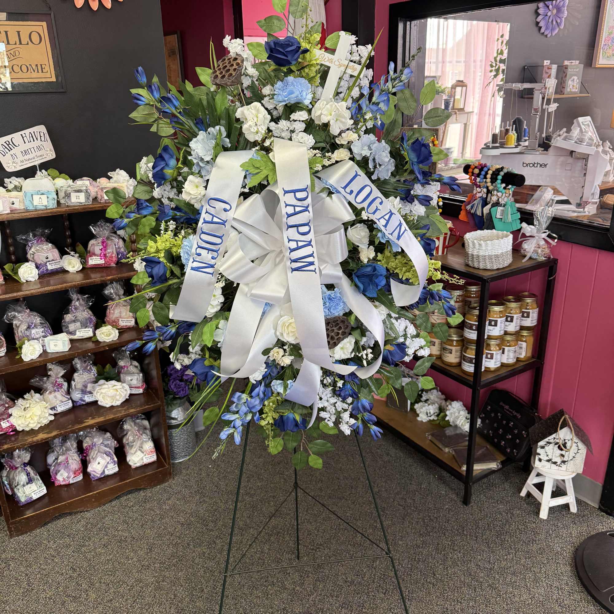 Large standing floral wreath with blue and white flowers and white ribbons