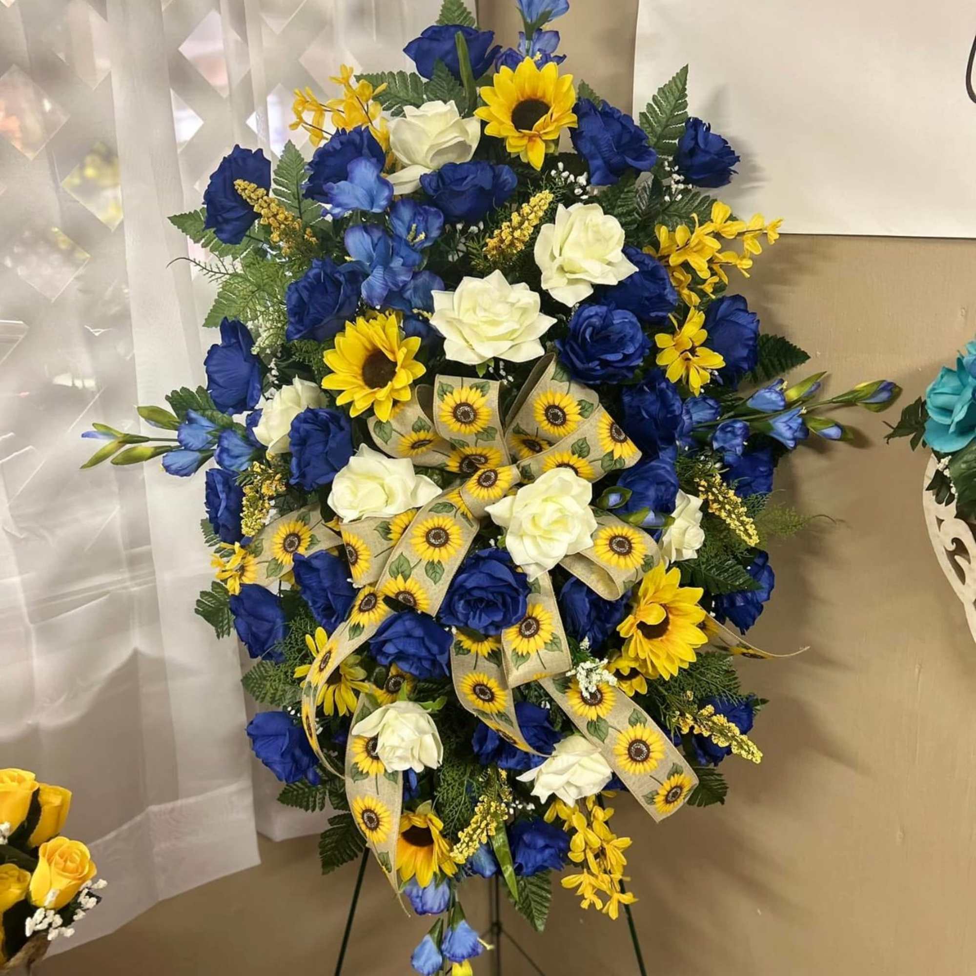 Large blue and yellow floral standing spray with white roses on an easel