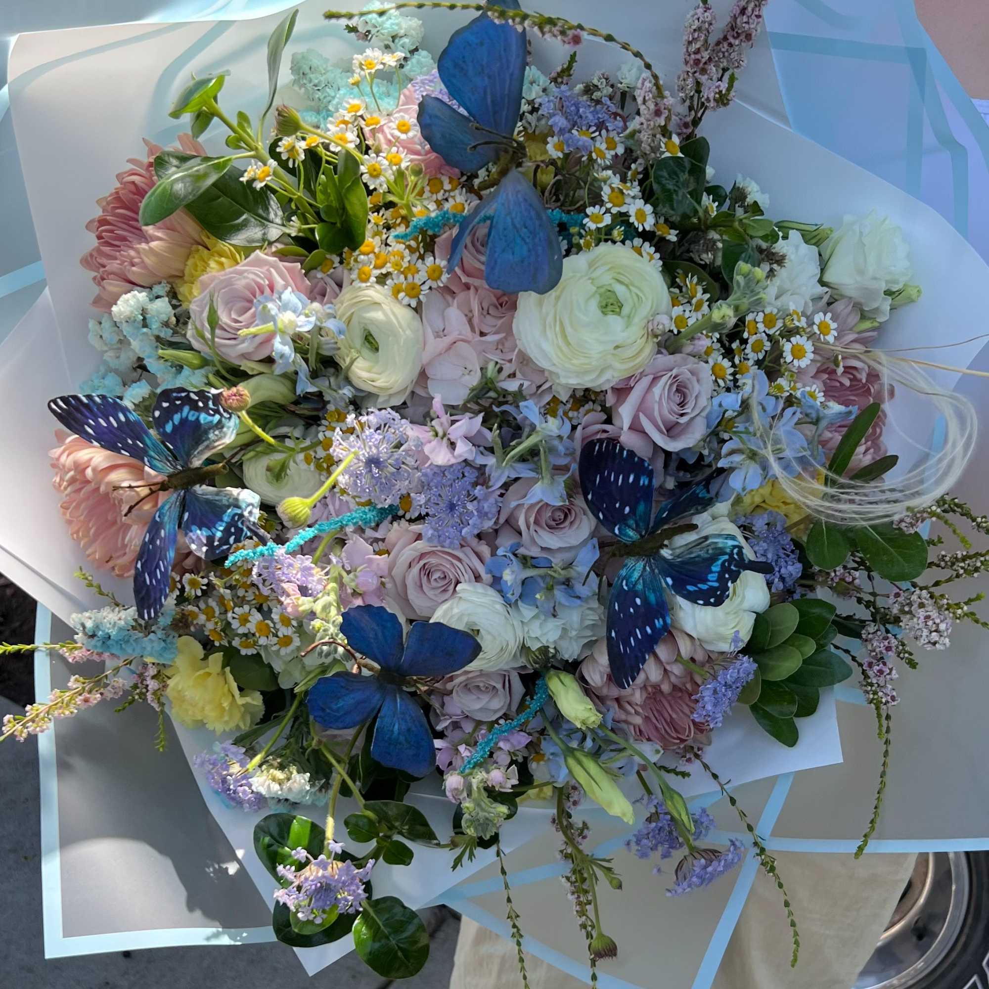 Large pastel bouquet with butterflies and mixed blooms wrapped in pale blue paper