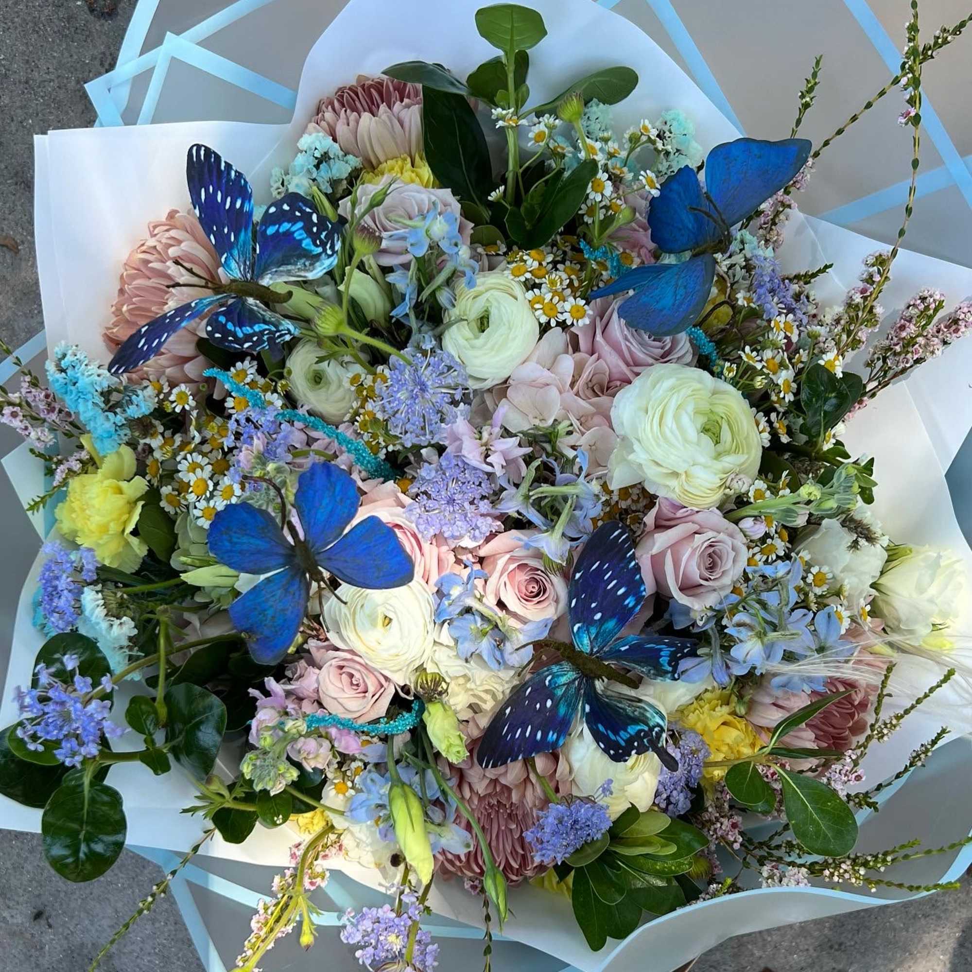 Mixed pastel bouquet with roses, ranunculus, and blue butterflies