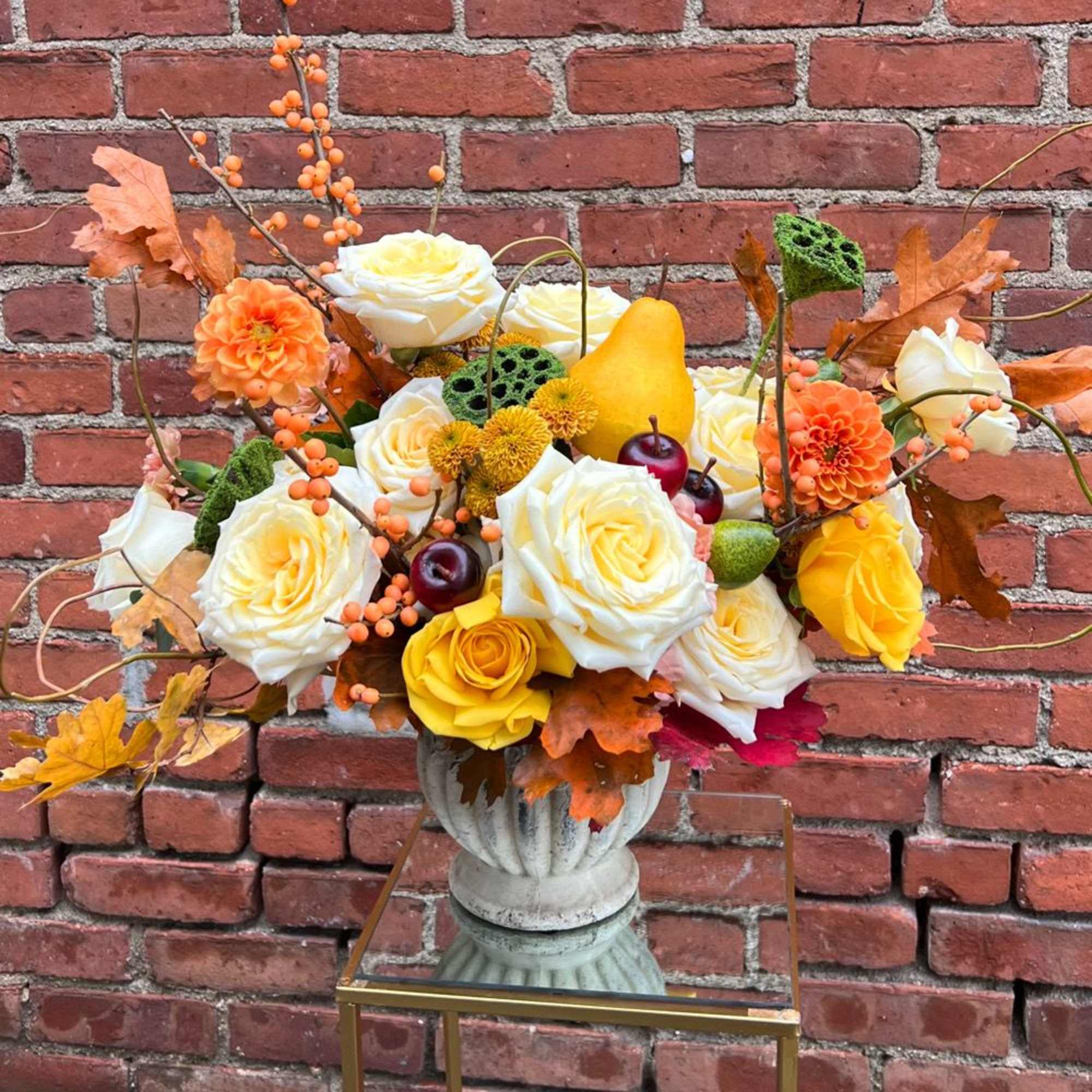 Autumn floral arrangement with roses, dahlias, and berries in a pedestal vase