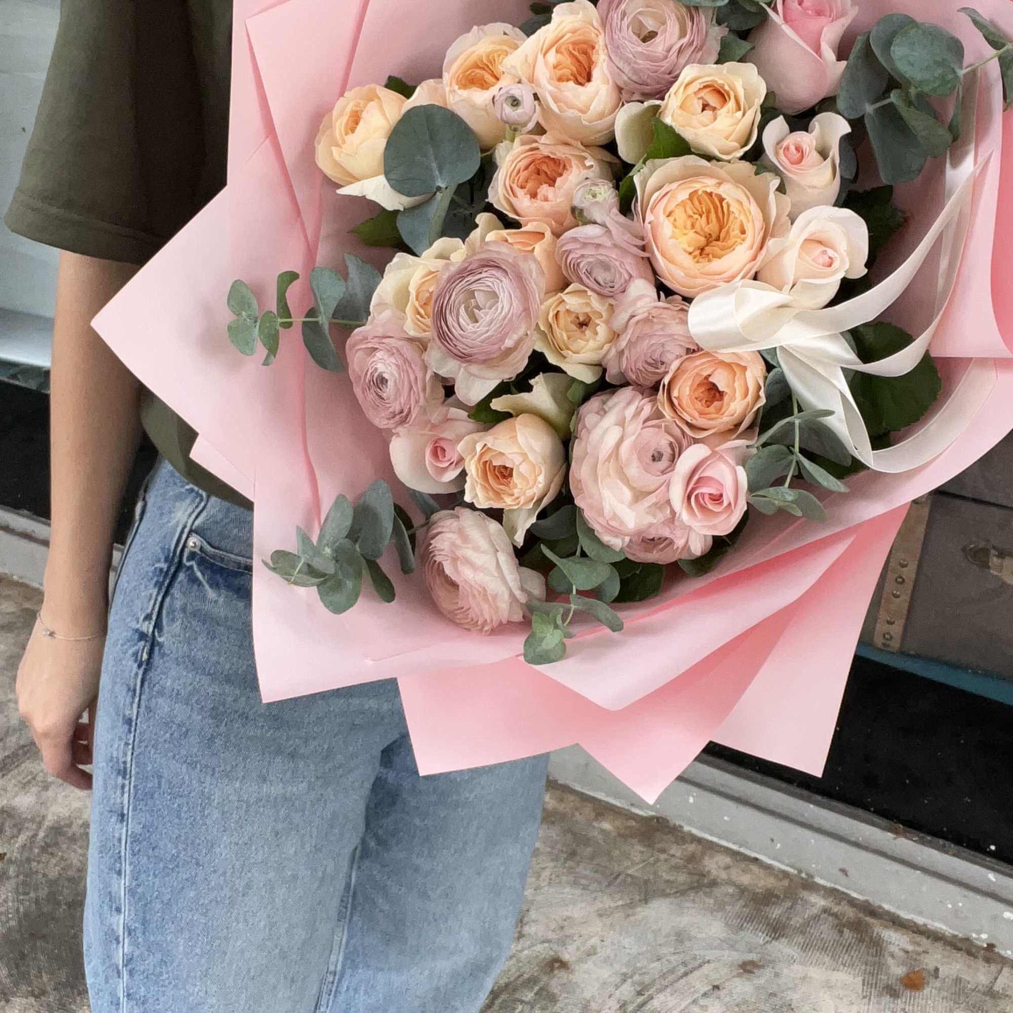 Large bouquet of blush and peach roses with pink wrapping