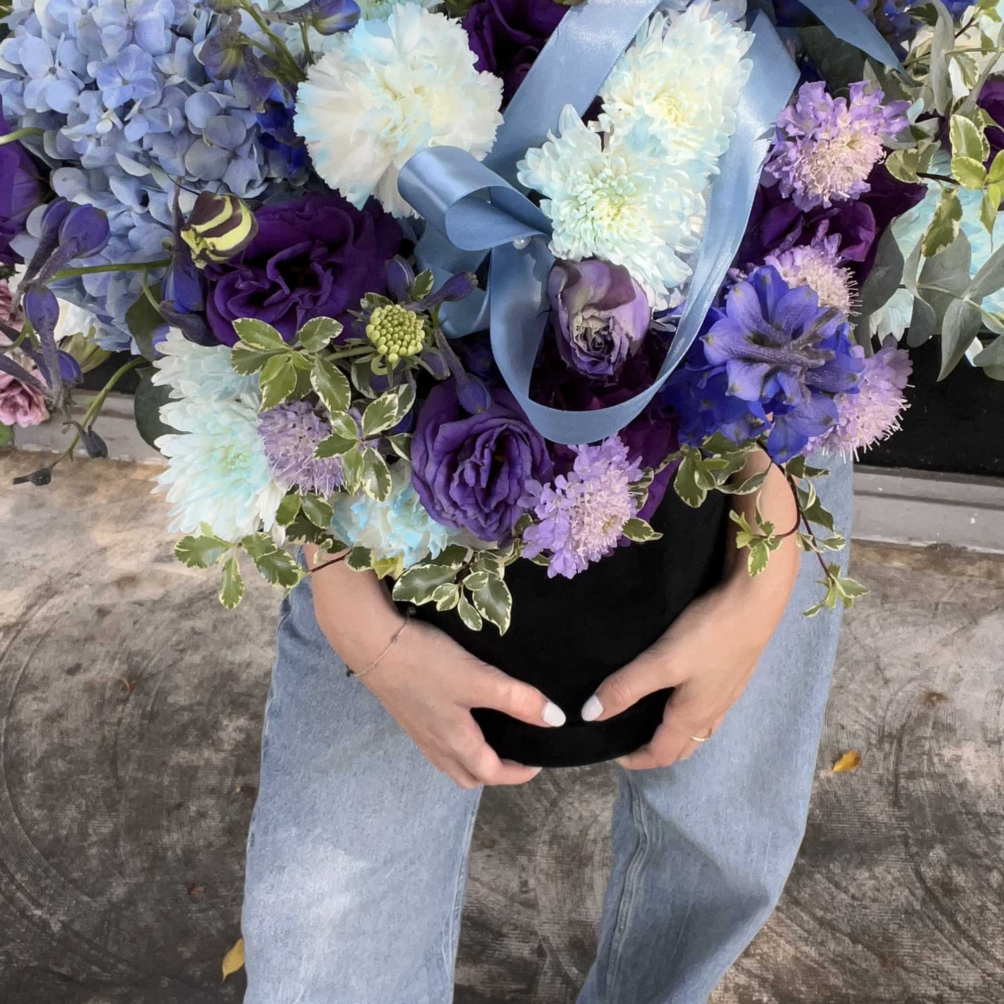 Large bouquet of blue, purple, and white flowers with a satin ribbon