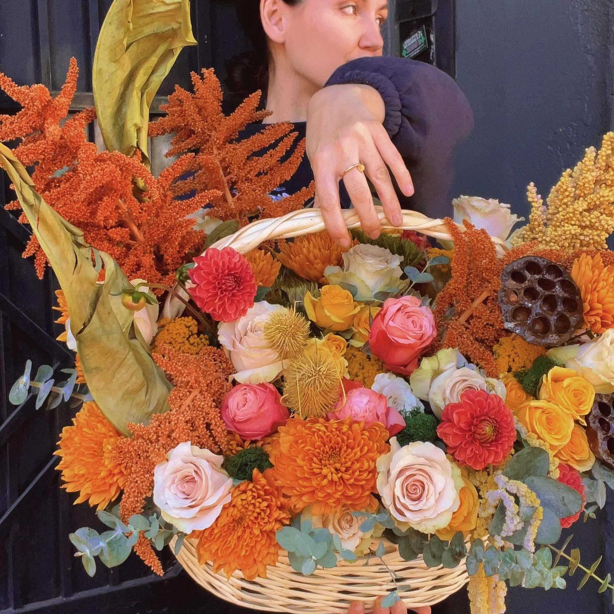 Woman holding a wicker basket filled with orange and pink flowers