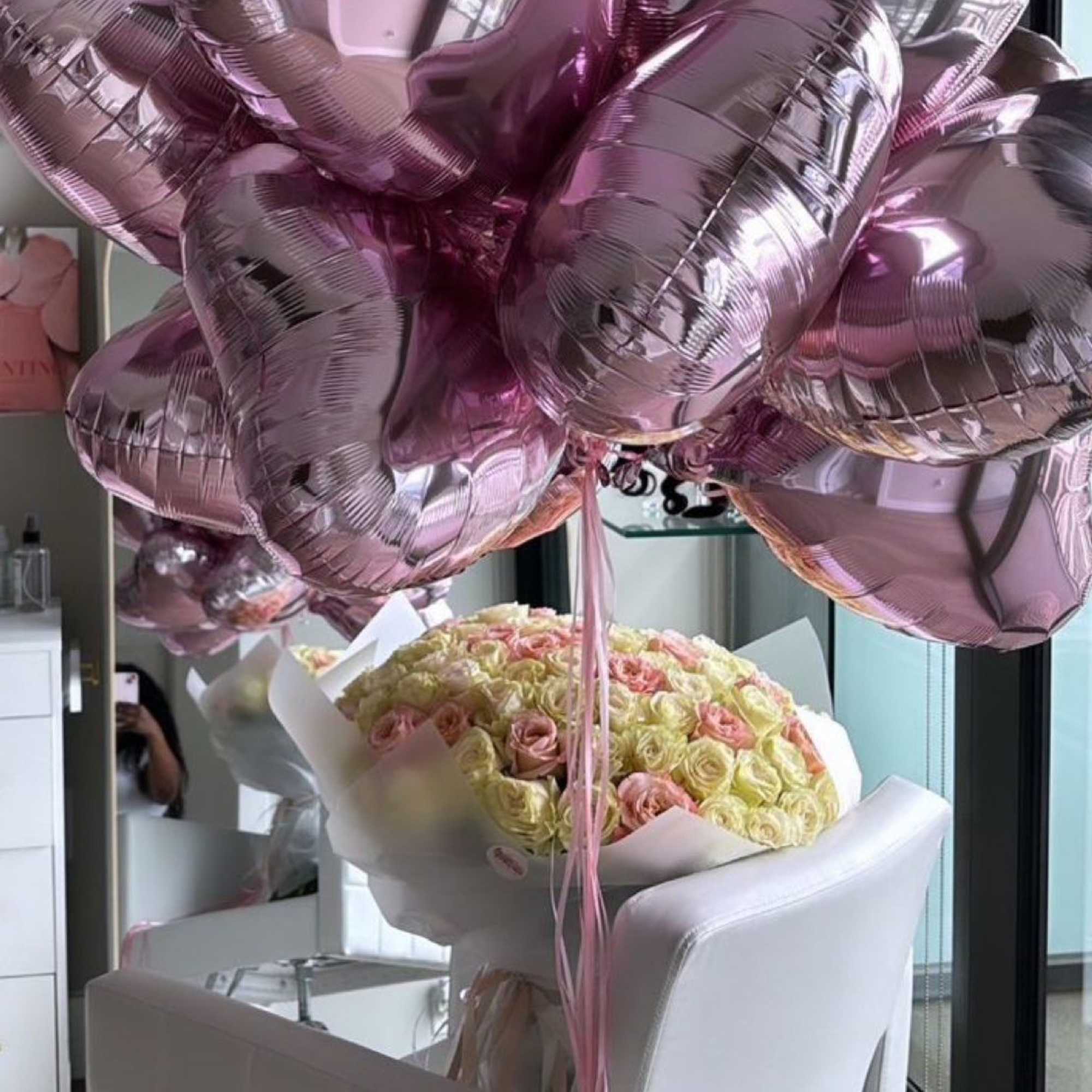 Bouquet of pale roses with pink heart-shaped balloons