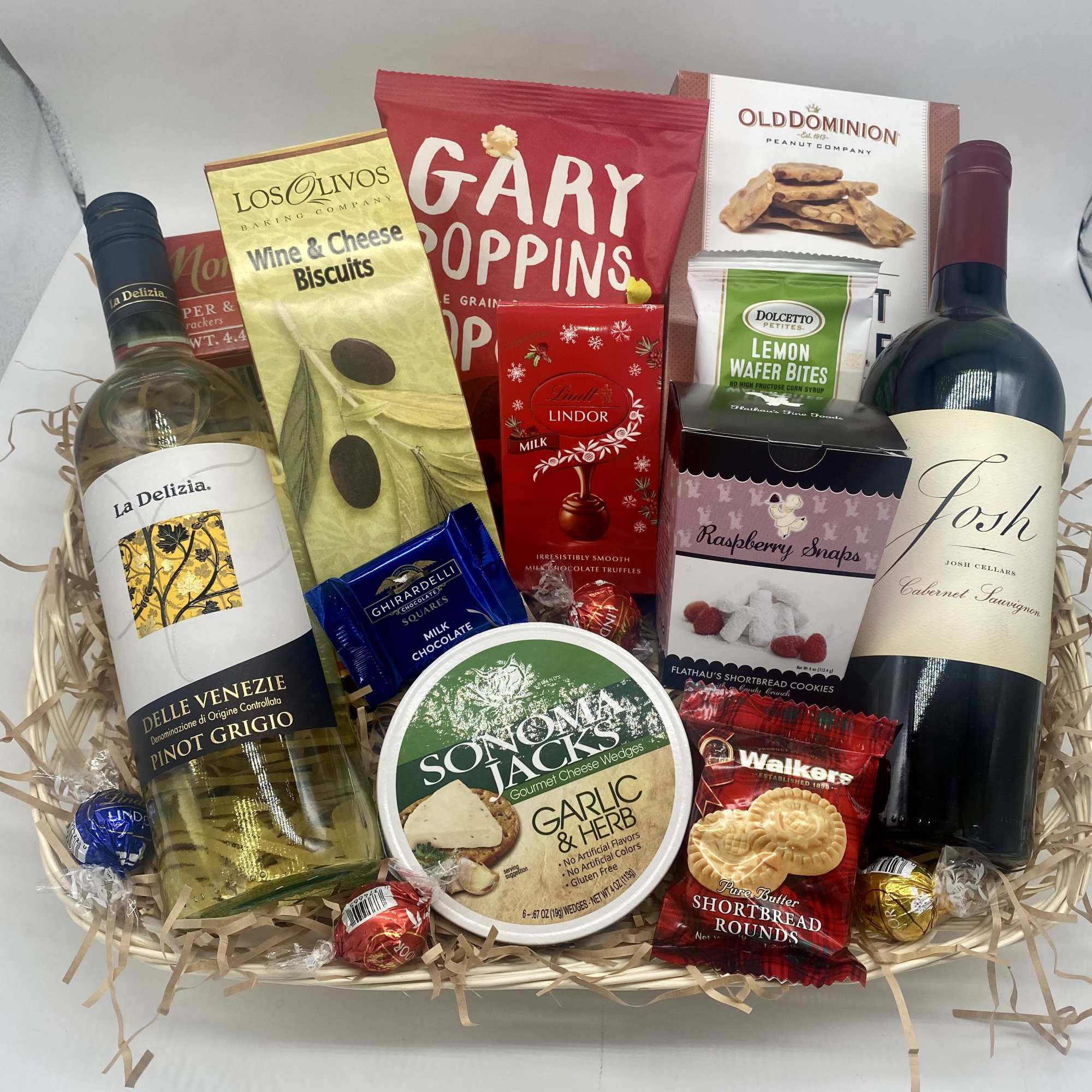 Gift basket with wine, chocolates, cookies, and crackers in a wicker tray