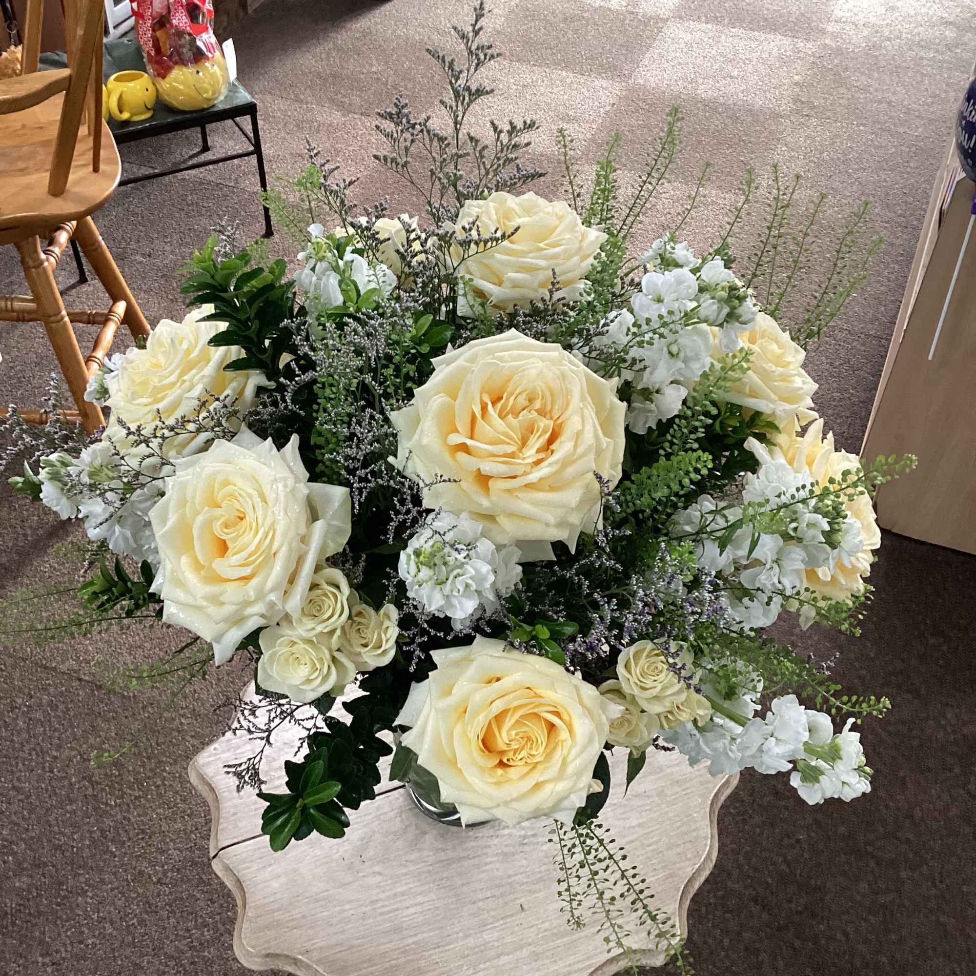 Cream rose arrangement in a clear vase on a small table