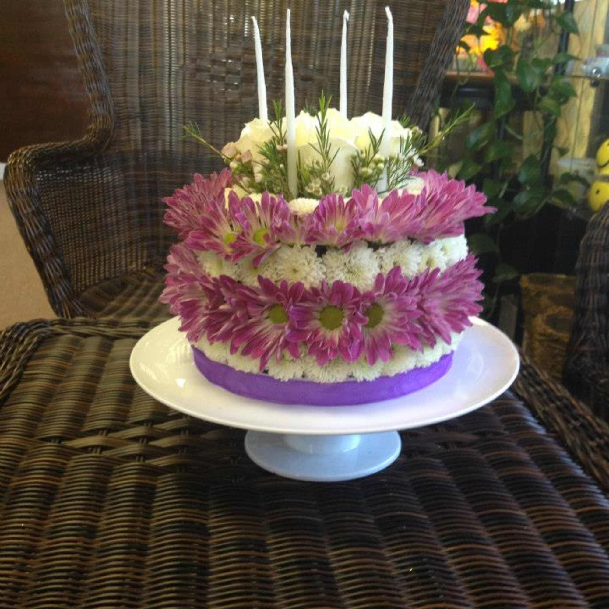 Round floral arrangement with pink and white flowers and tall white candles on a pedestal stand