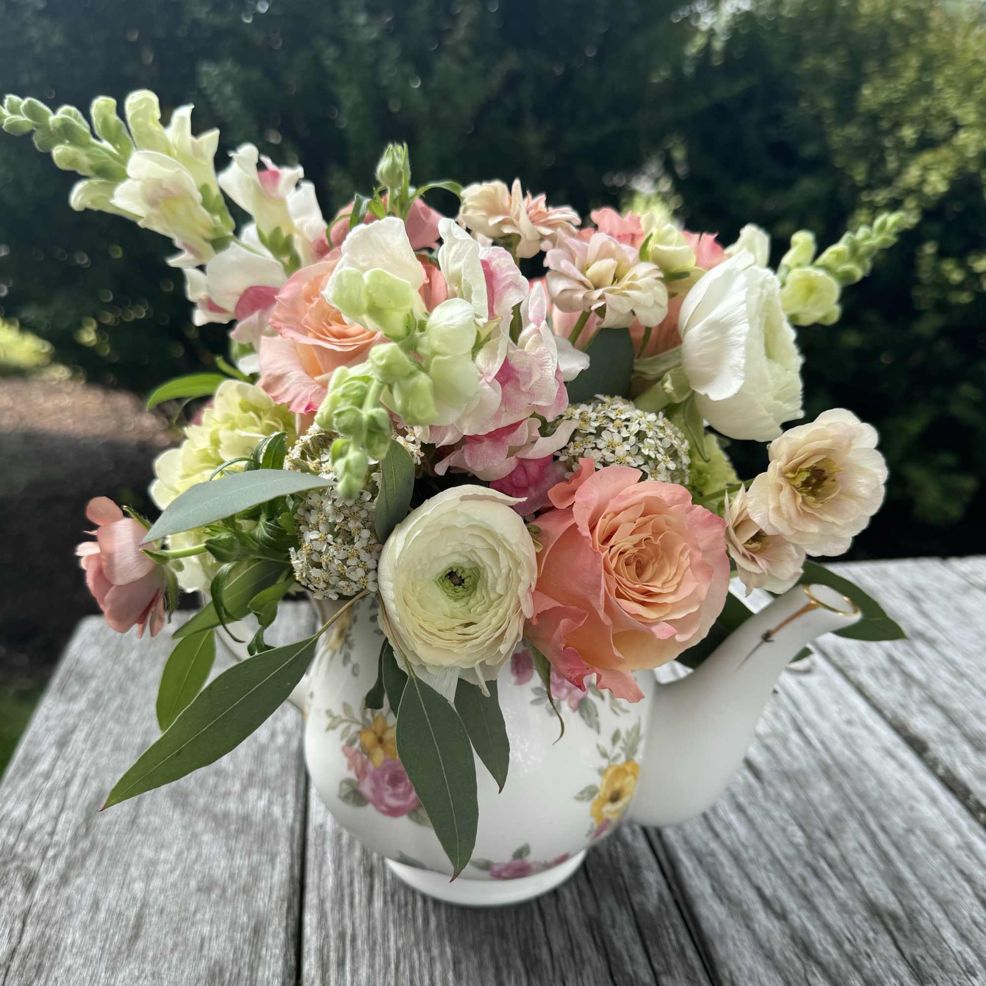 Pastel flower arrangement in a floral teapot vase