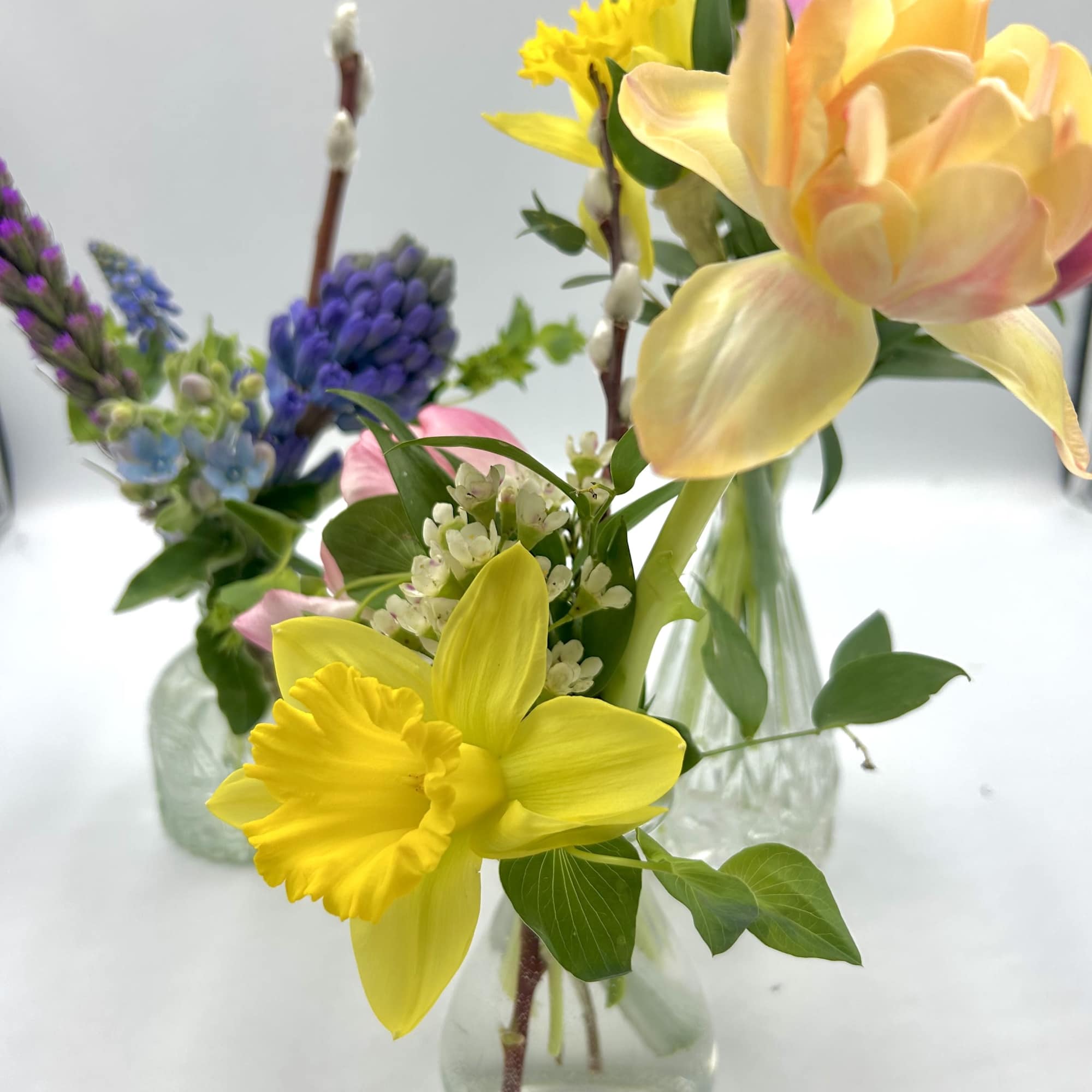 Small glass vases with colorful spring flowers