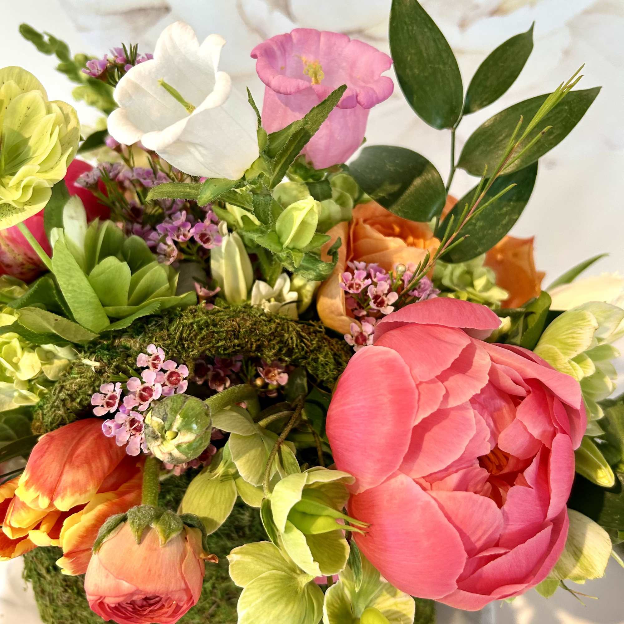 Mixed bouquet with pink, white, and orange blooms in a moss base