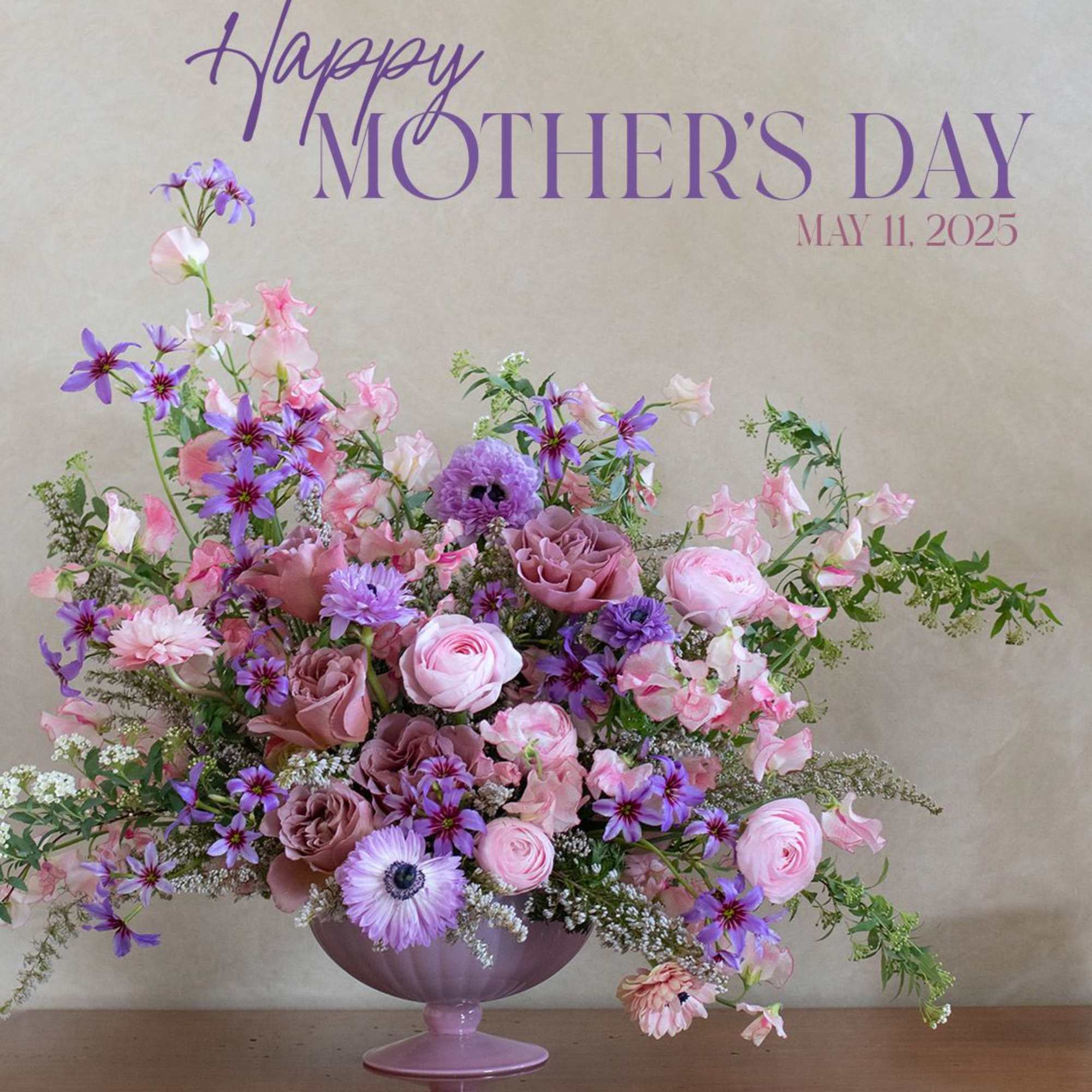 Pink and purple floral arrangement in a lavender pedestal vase