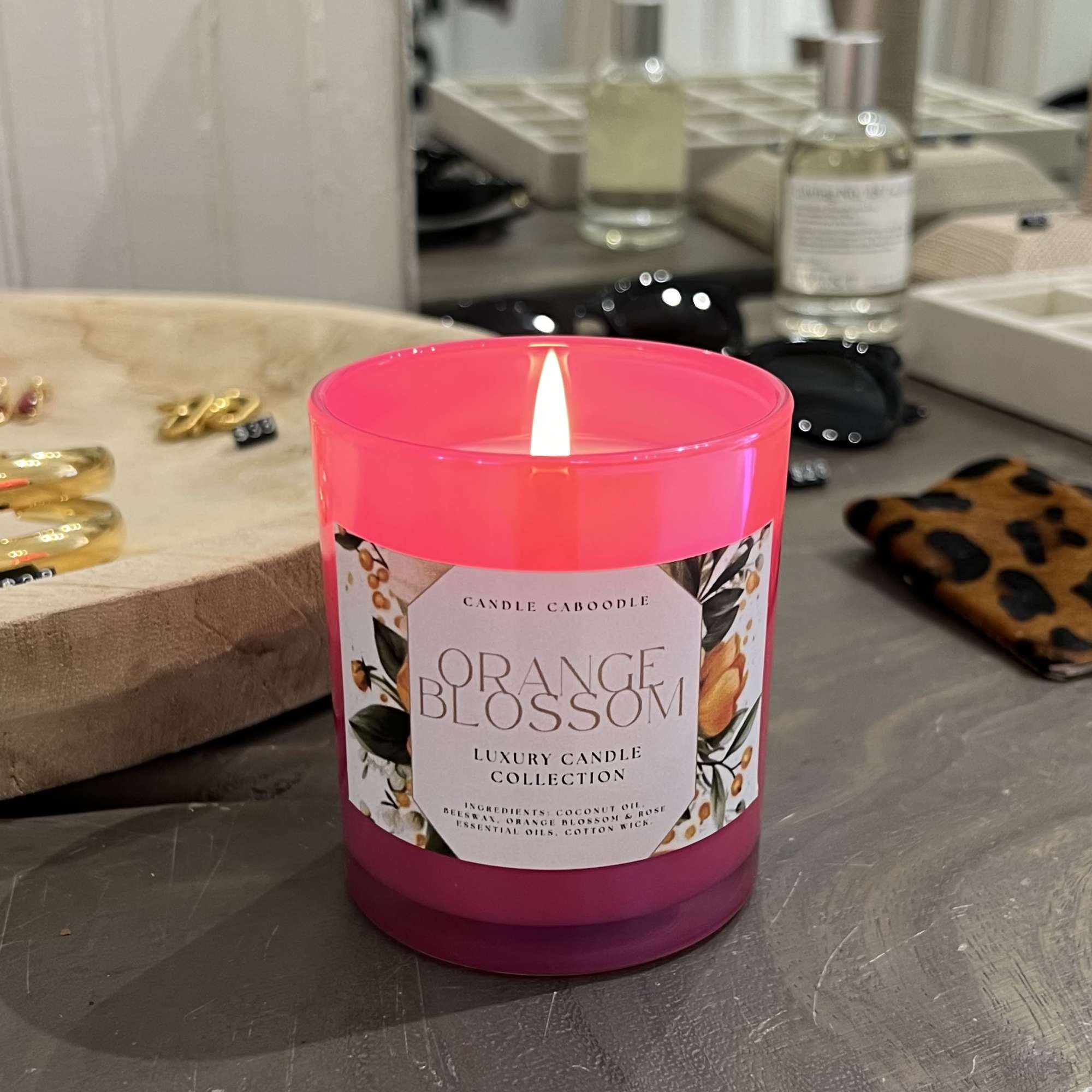 Lit pink candle in a glass jar labeled Orange Blossom