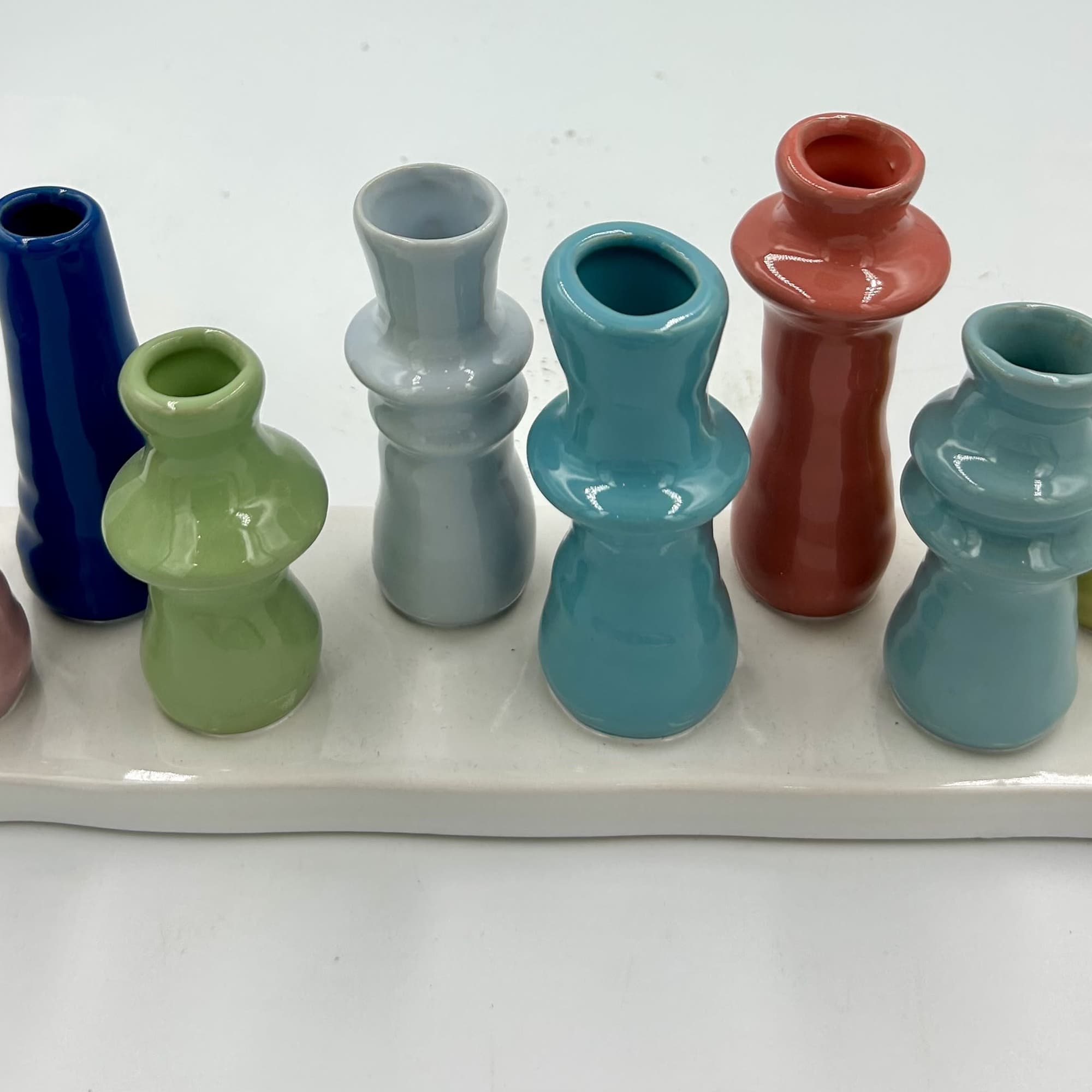 Colorful miniature ceramic vases arranged on a white tray