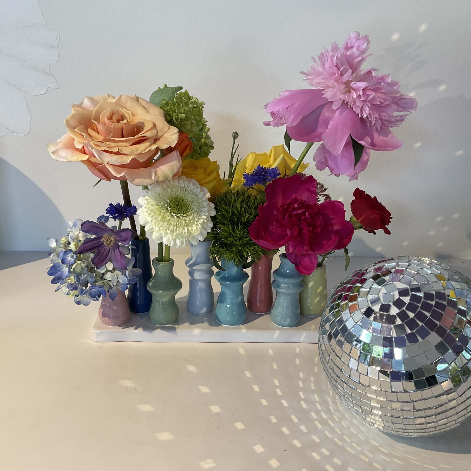 Colorful mixed flowers in small pastel vases with a mirrored disco ball