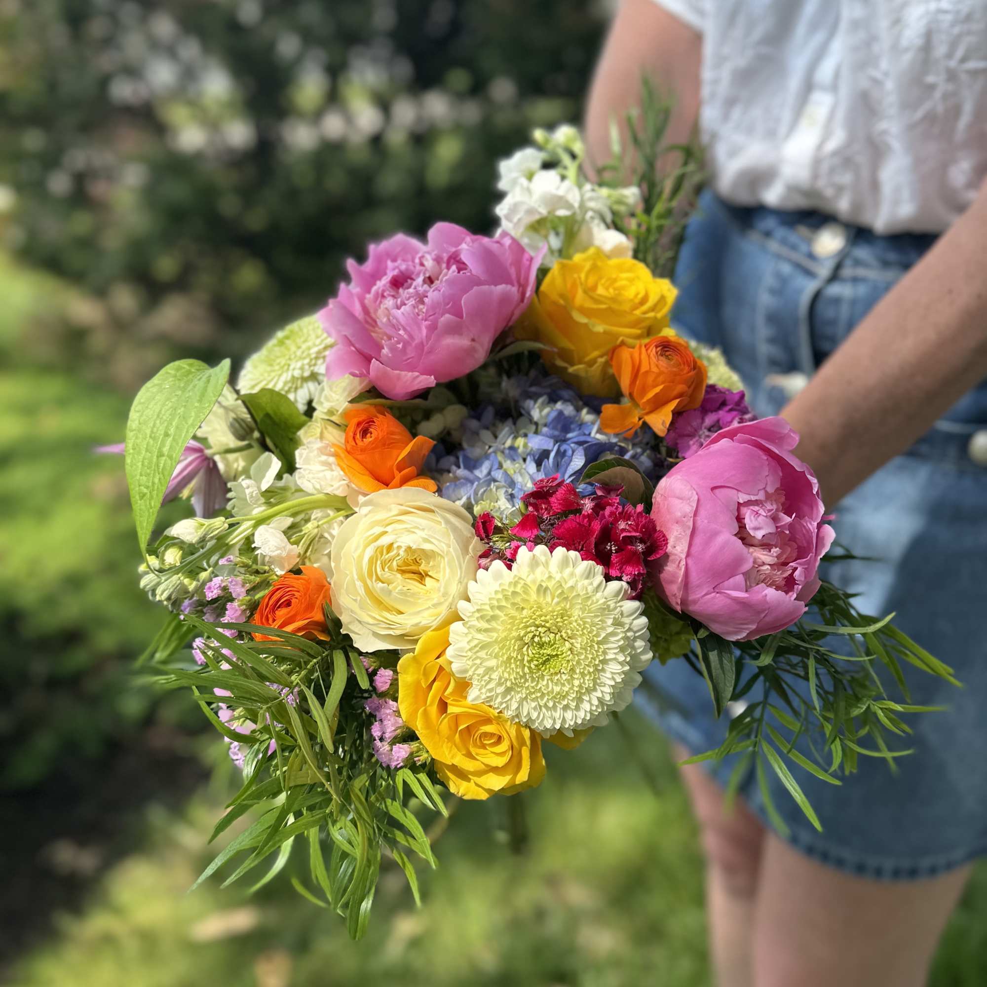 Handheld bouquet of pink, yellow, orange, and white flowers