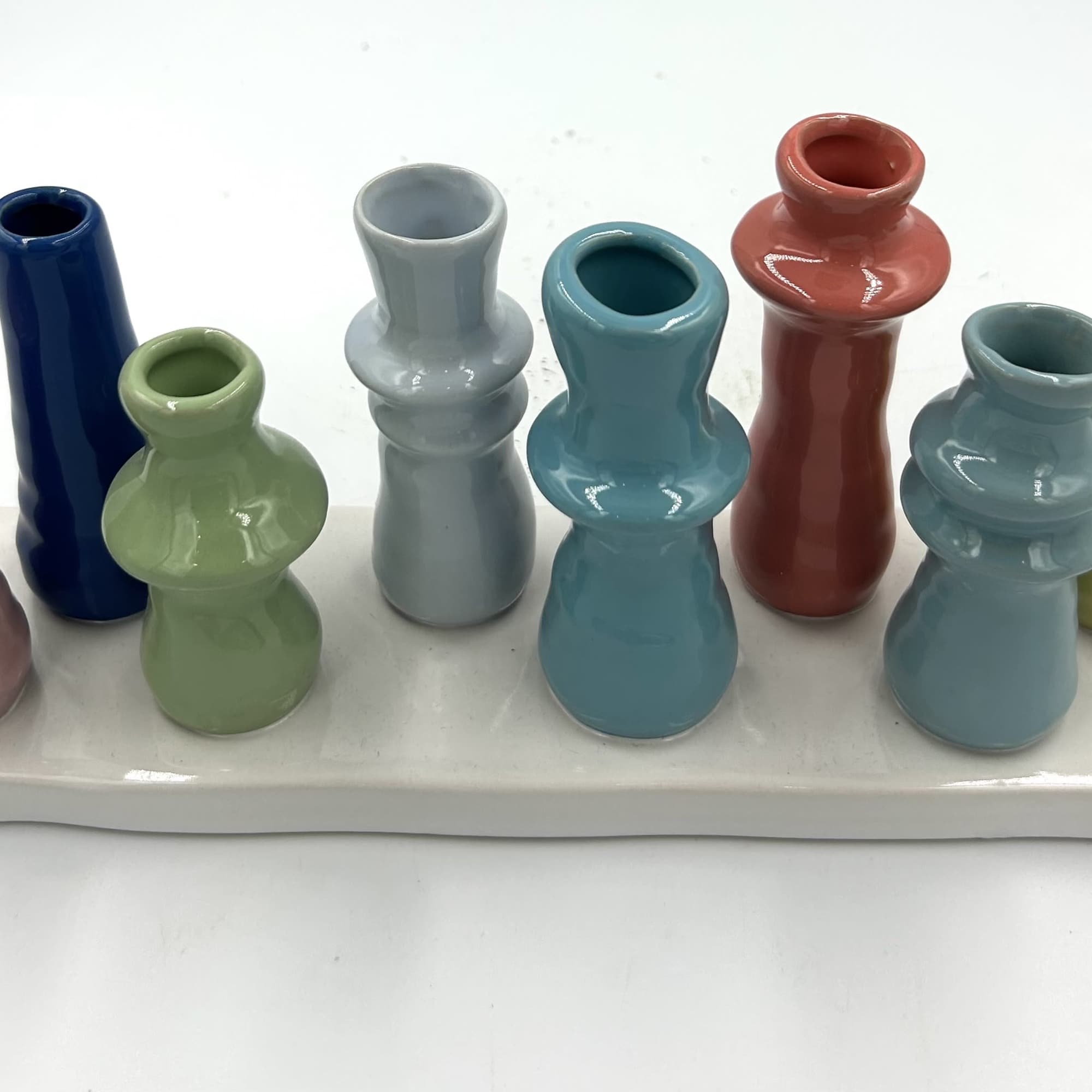 Colorful ceramic bud vases arranged on a white tray