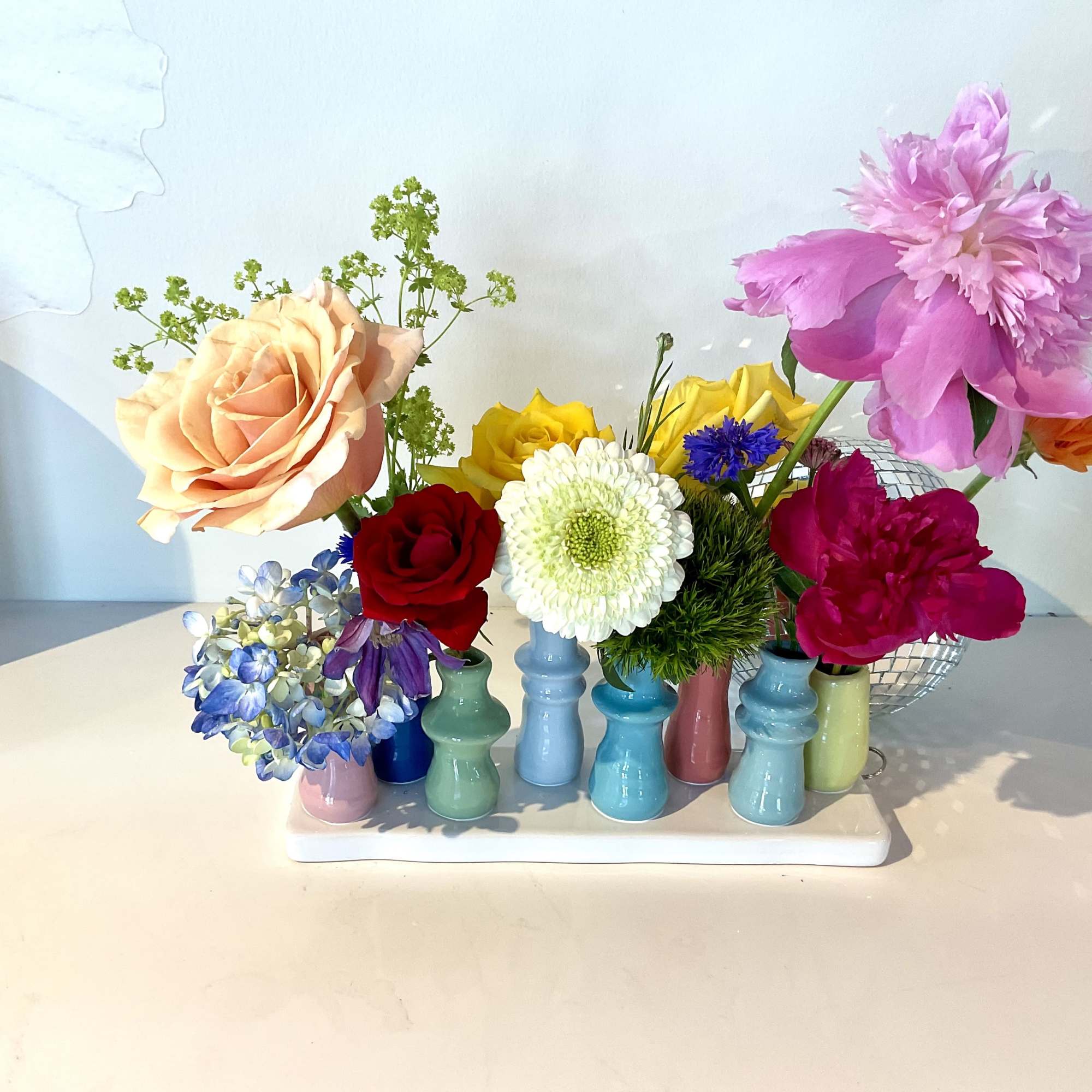 Colorful mixed flower arrangement in small pastel vases