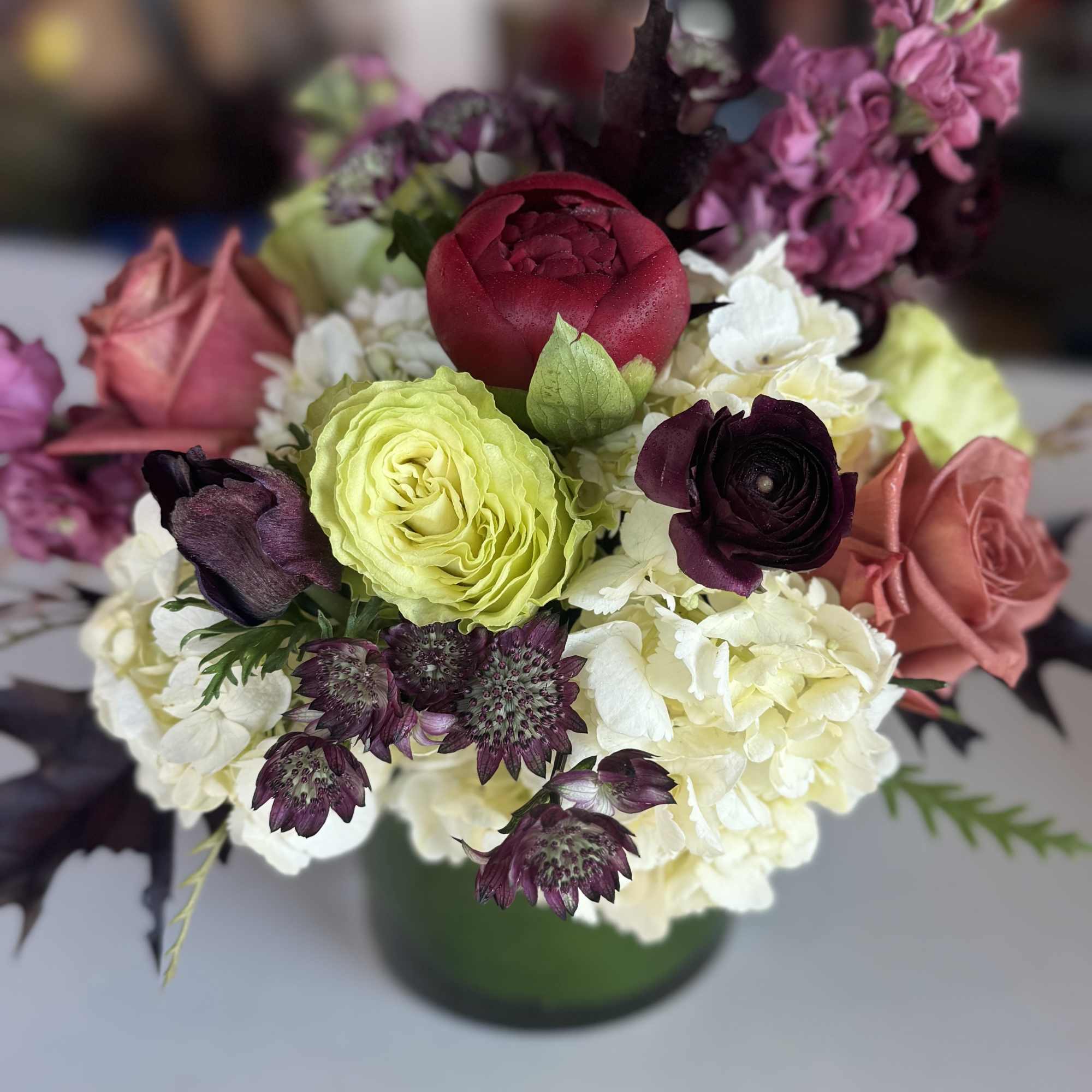 Mixed bouquet of roses, hydrangeas, and astrantia in a green vase