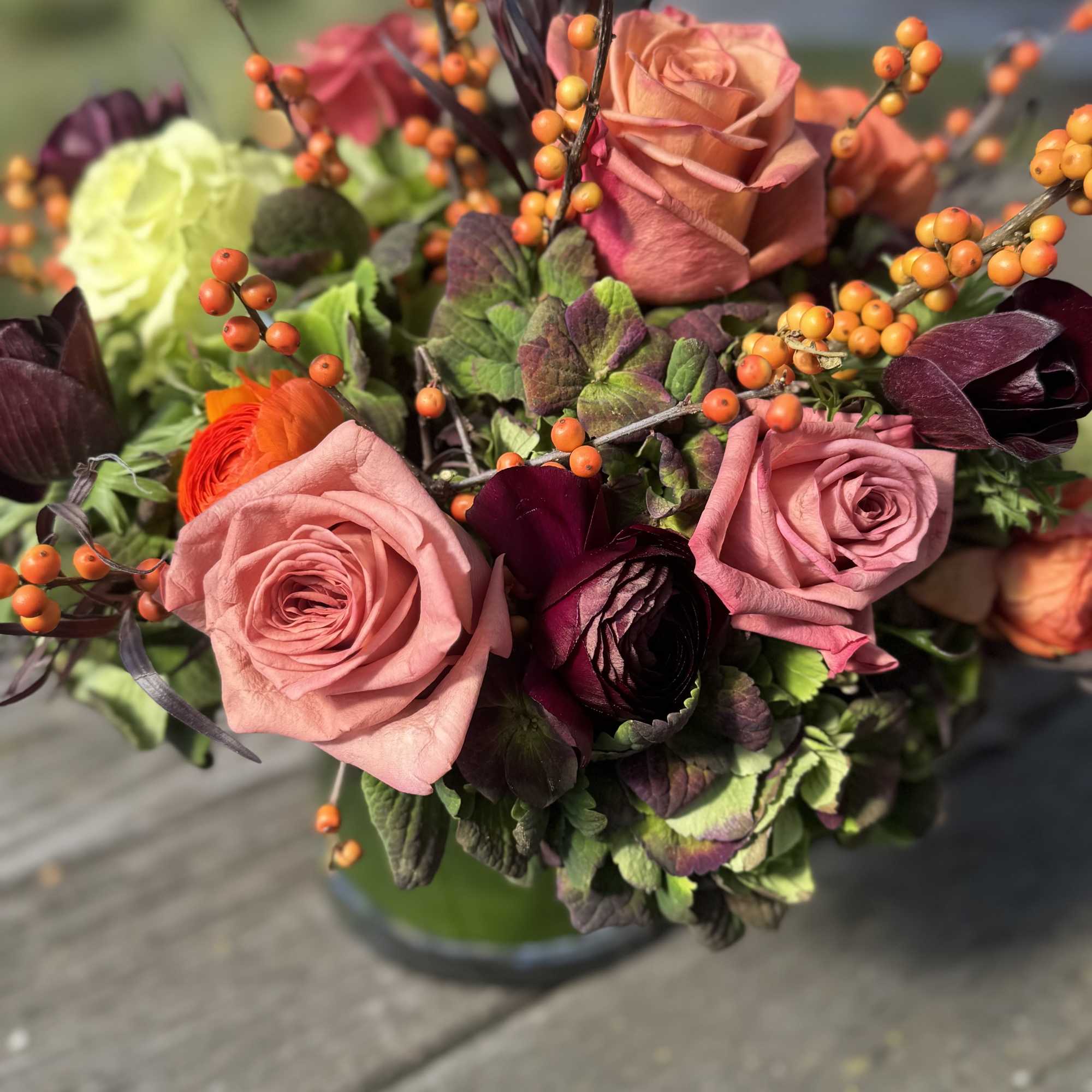 Bouquet of pink roses with orange berry stems and dark foliage