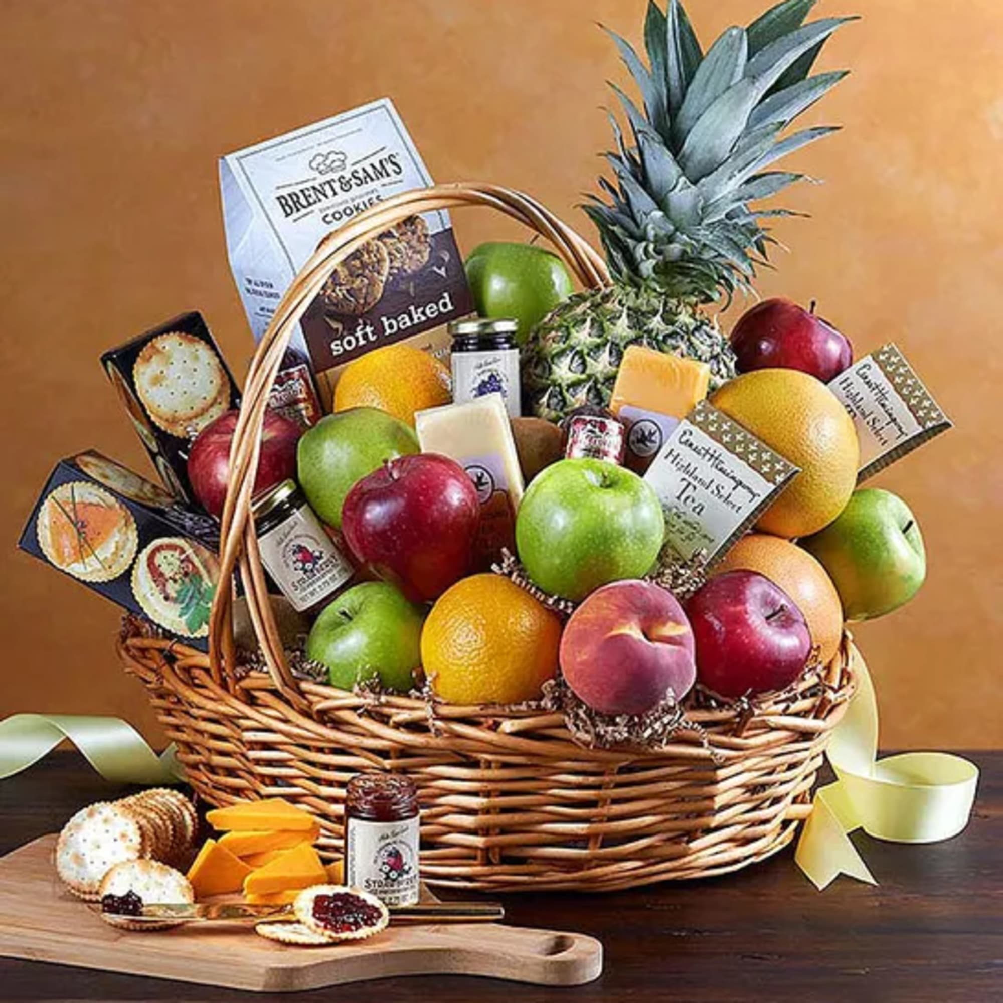 Fruit and snack gift basket with apples, citrus, pineapple, cookies, and tea