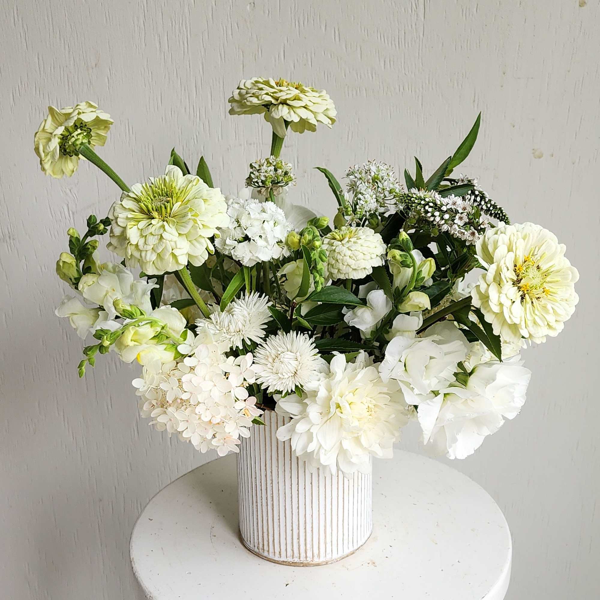 White and pale green flower arrangement in a ribbed vase