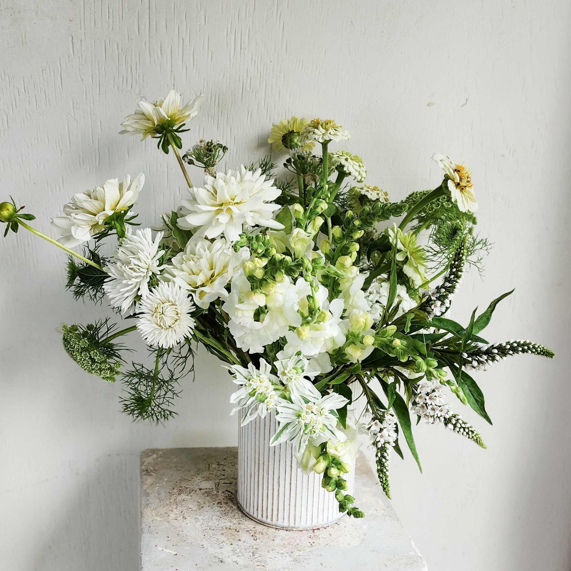 White floral arrangement in a ribbed white vase