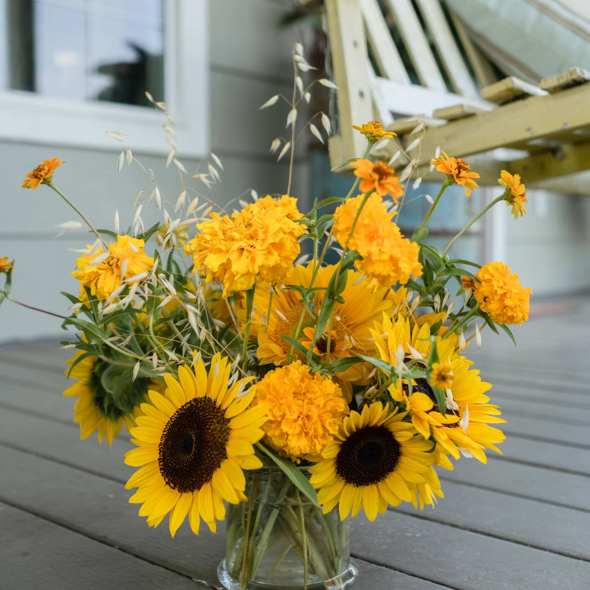 Yellow sunflowers and marigolds arranged in a clear glass vase