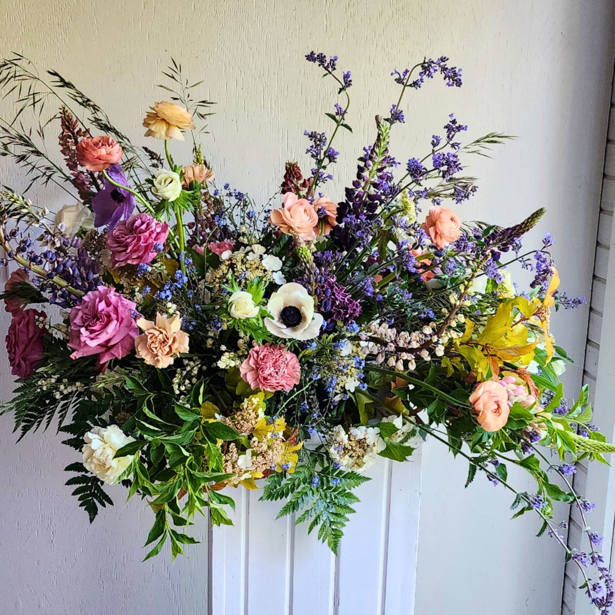 Large mixed floral arrangement with pink, peach, white, and purple blooms