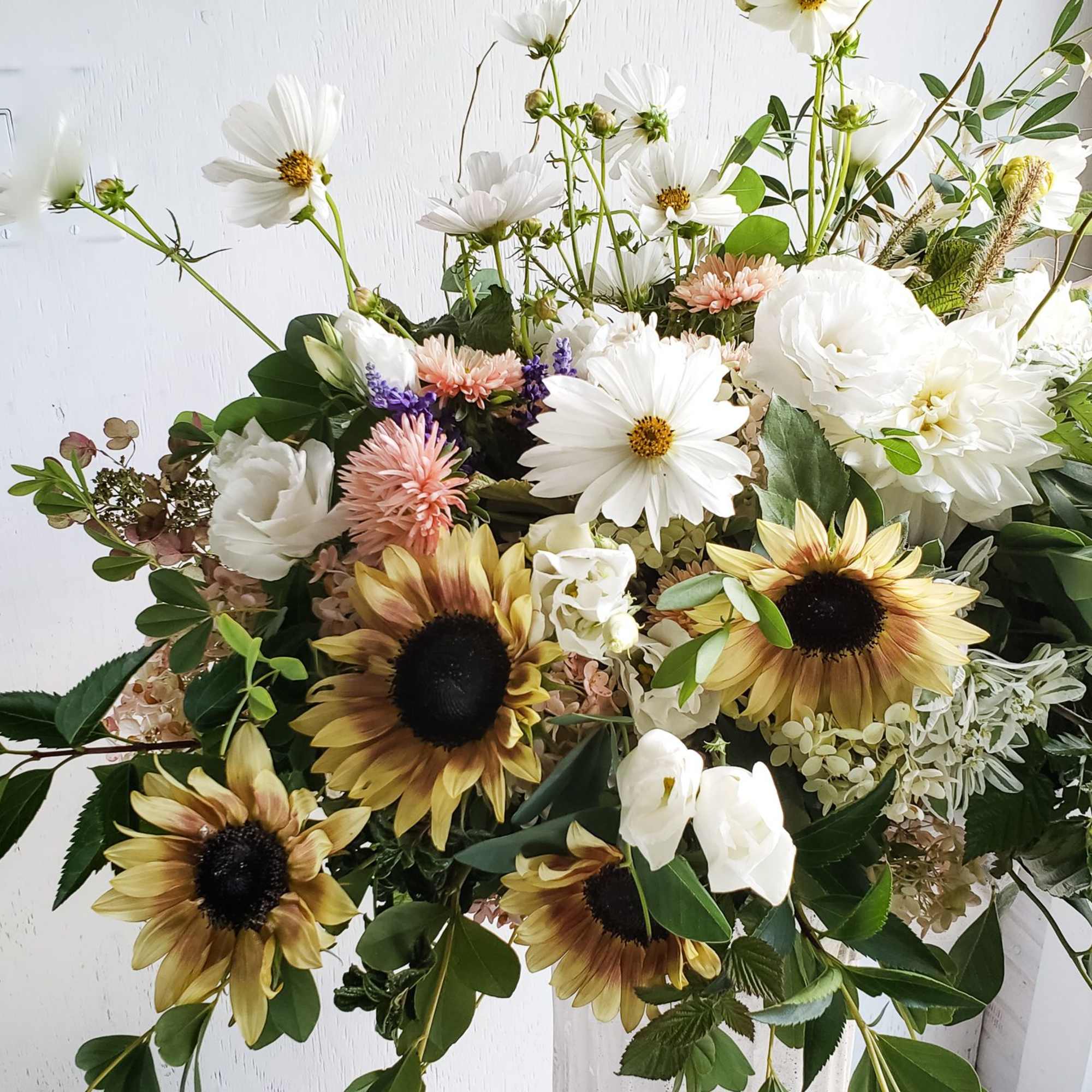 Large bouquet of white daisies, sunflowers, and pale pink blooms