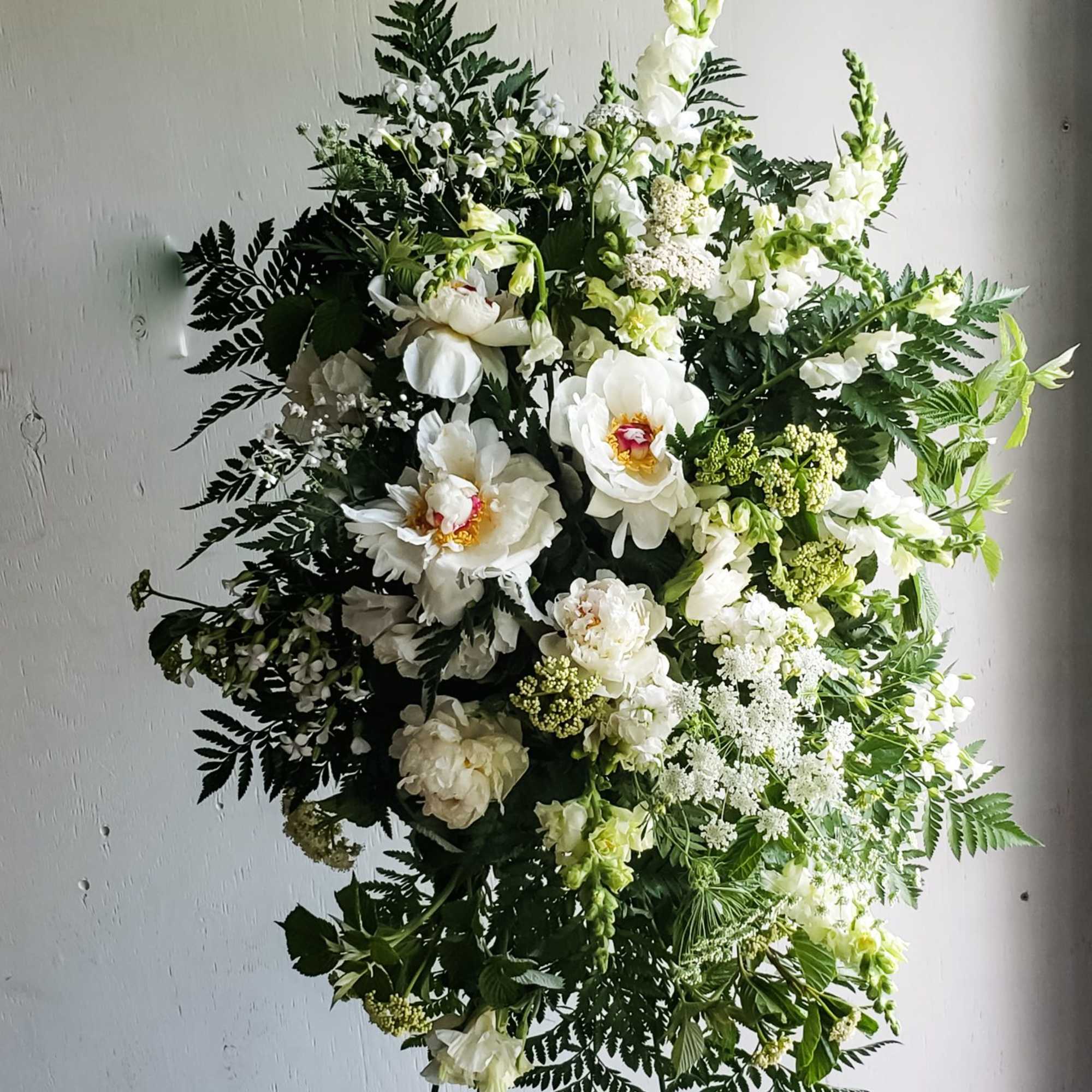 Large white floral standing spray with mixed greenery on an easel