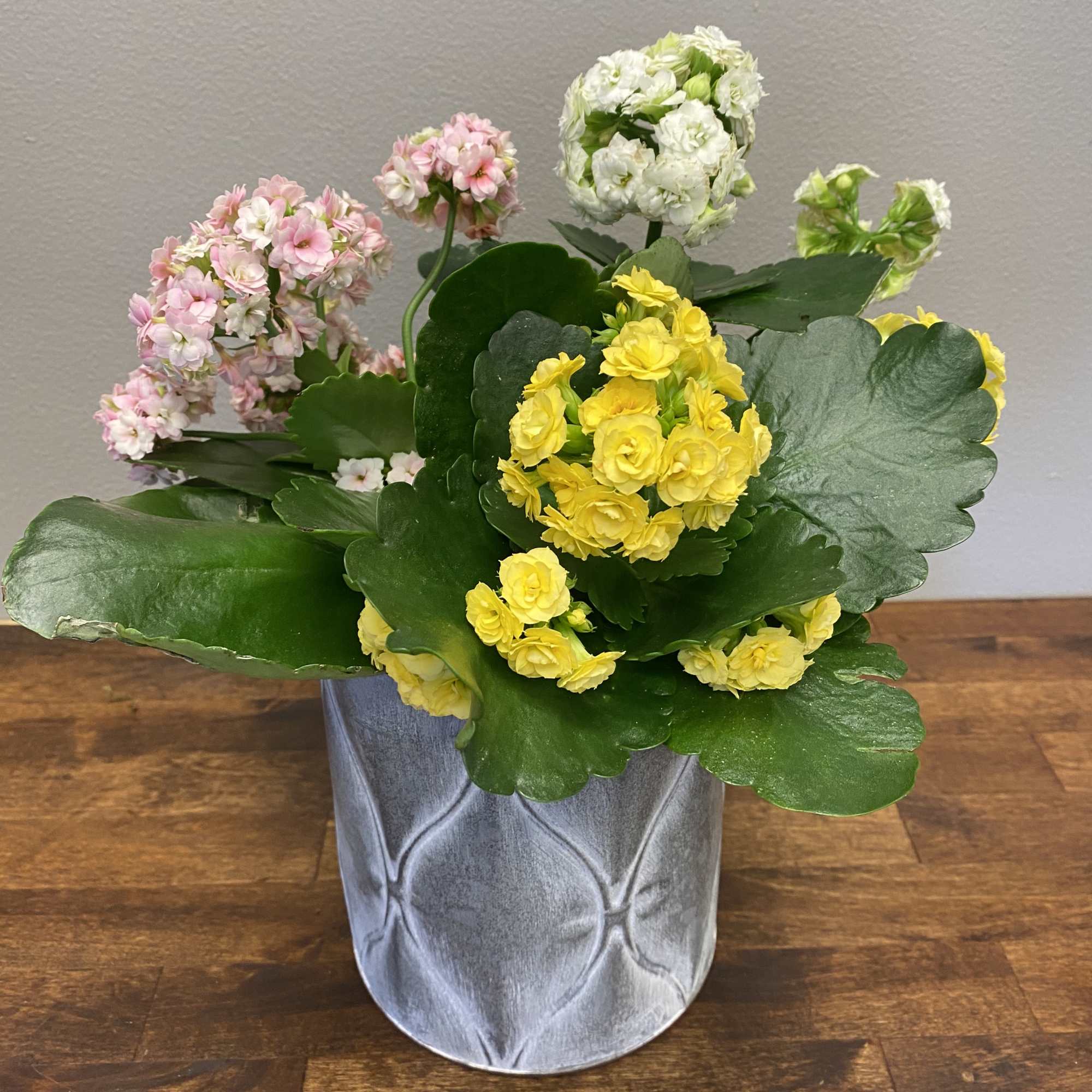 Potted arrangement of yellow, pink, and white flowers in a gray container