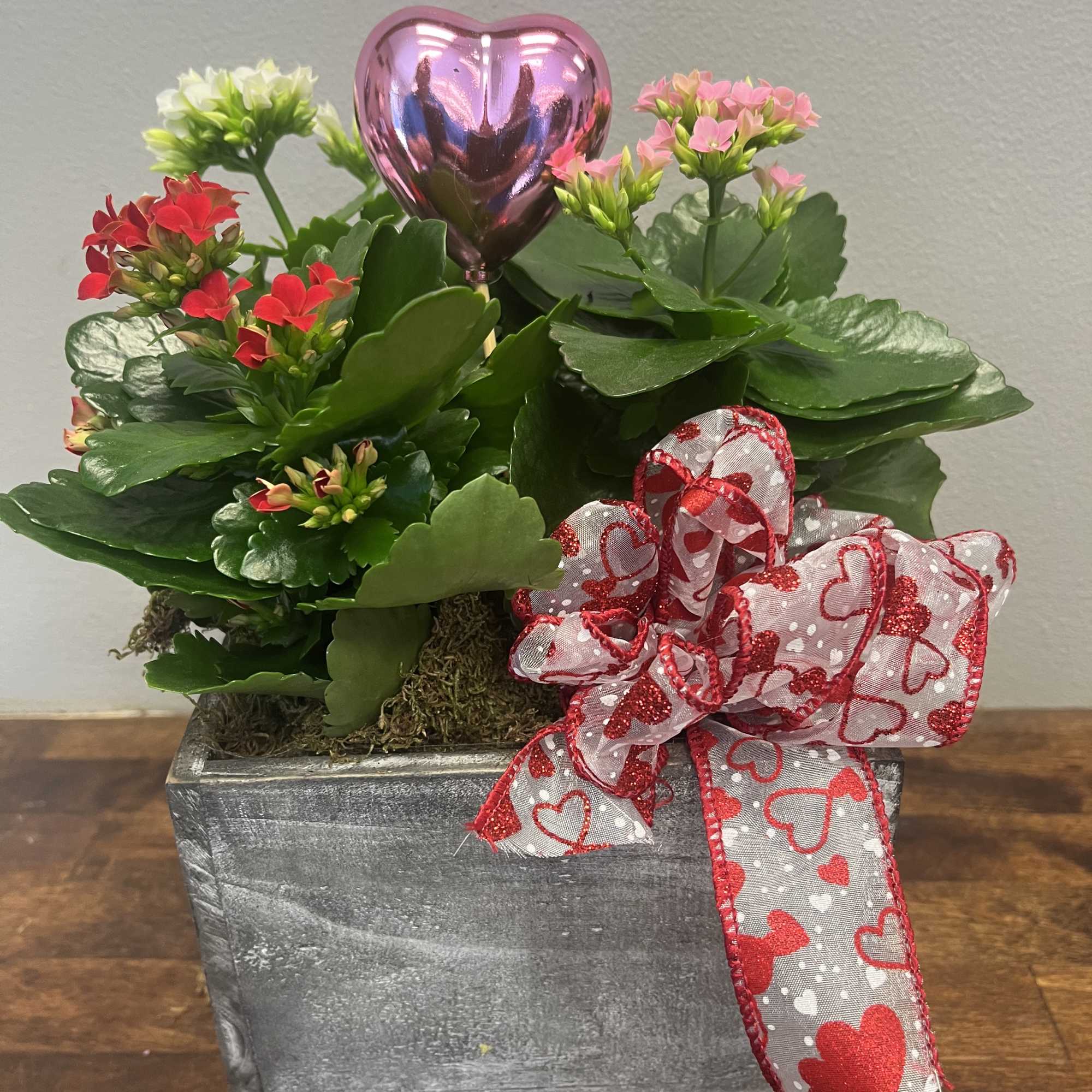 Potted flowering plant with pink and red blooms, a heart balloon, and a heart ribbon