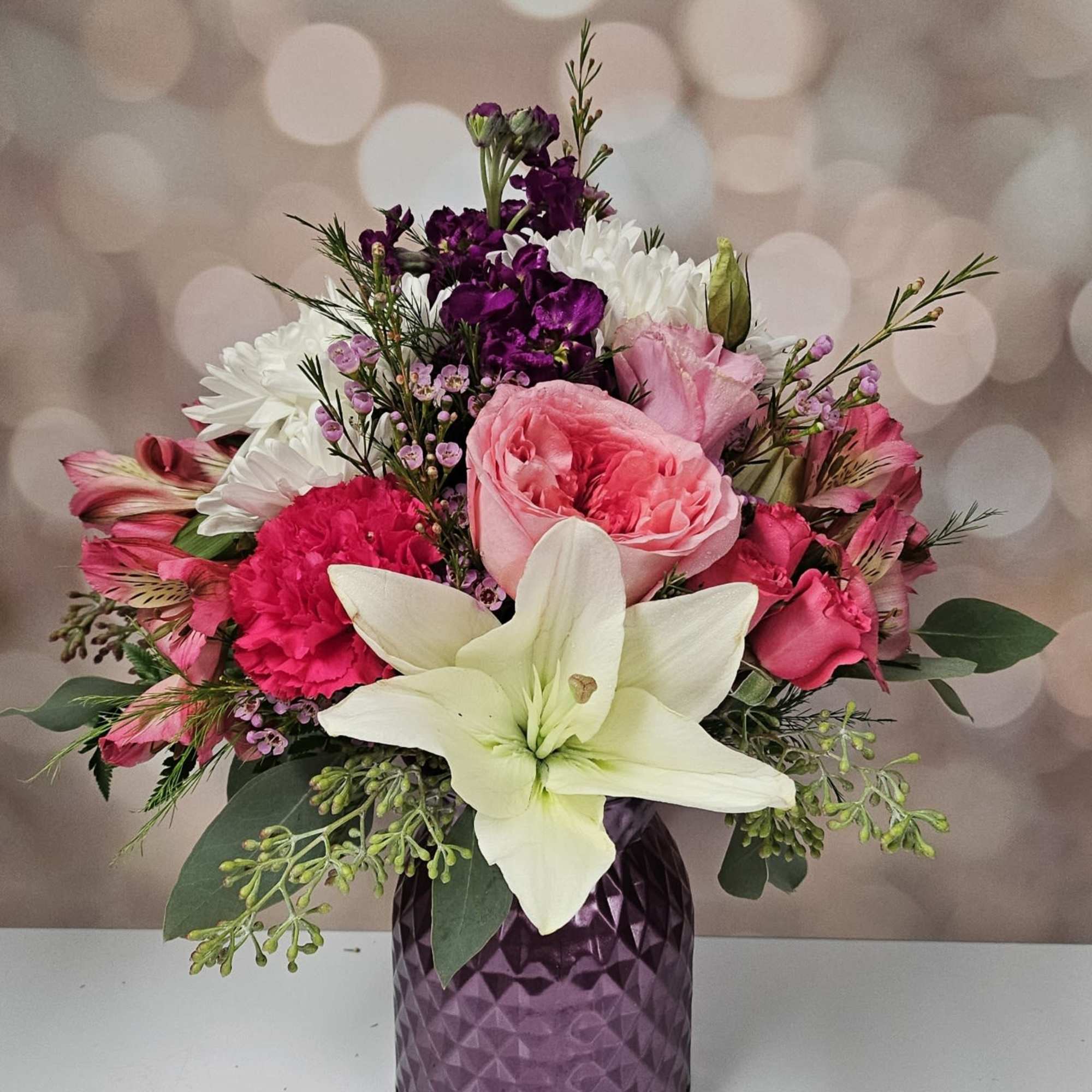 Mixed pink, white, and purple bouquet in a purple vase
