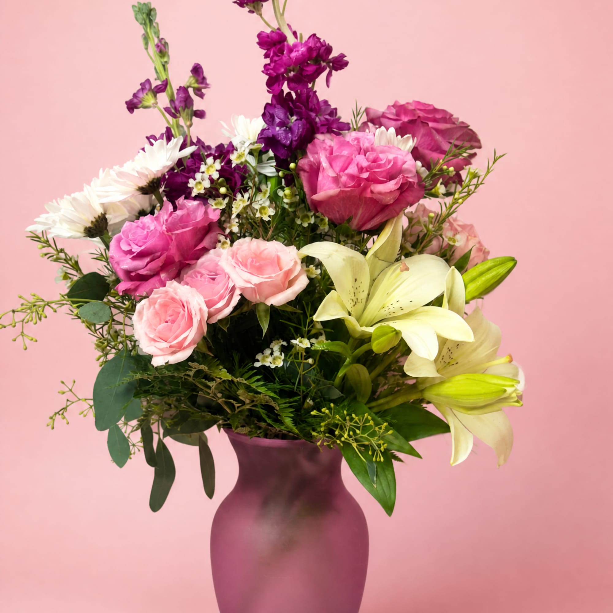 Pink and purple bouquet with lilies and roses in a purple vase