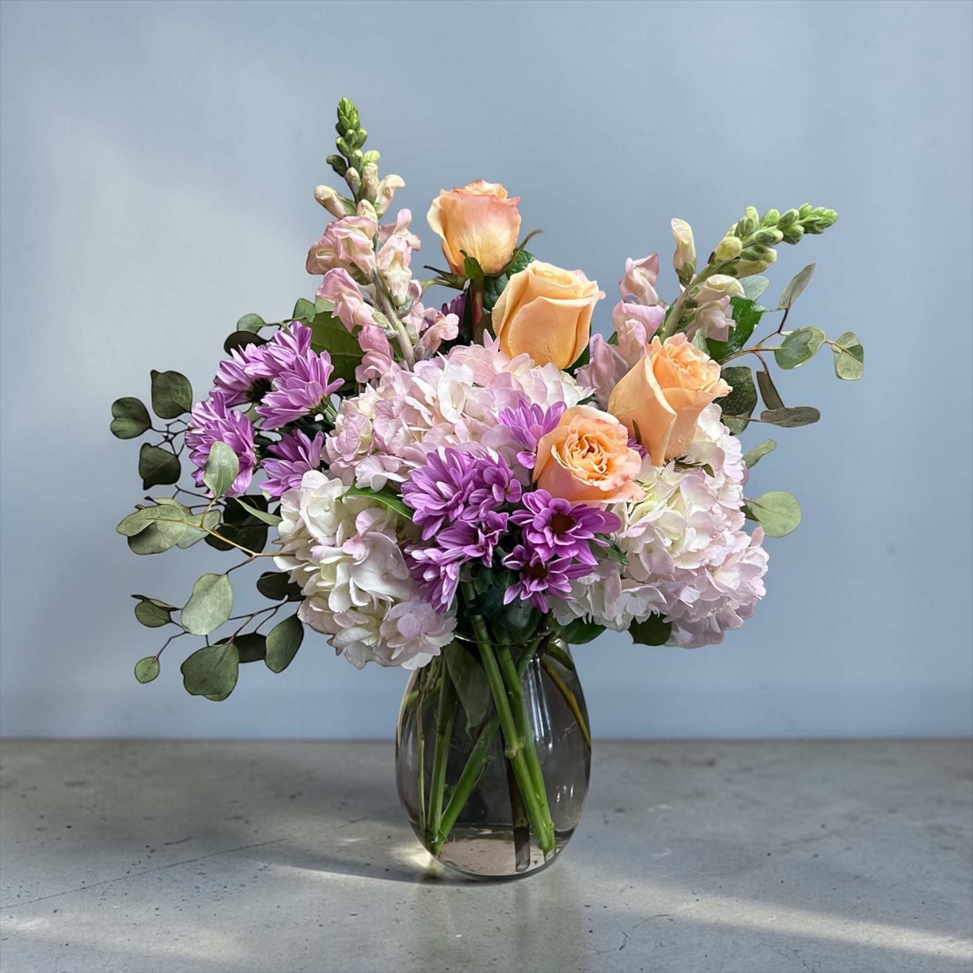 Peach roses meet pale pink and white hydrangeas in a soft, garden-style