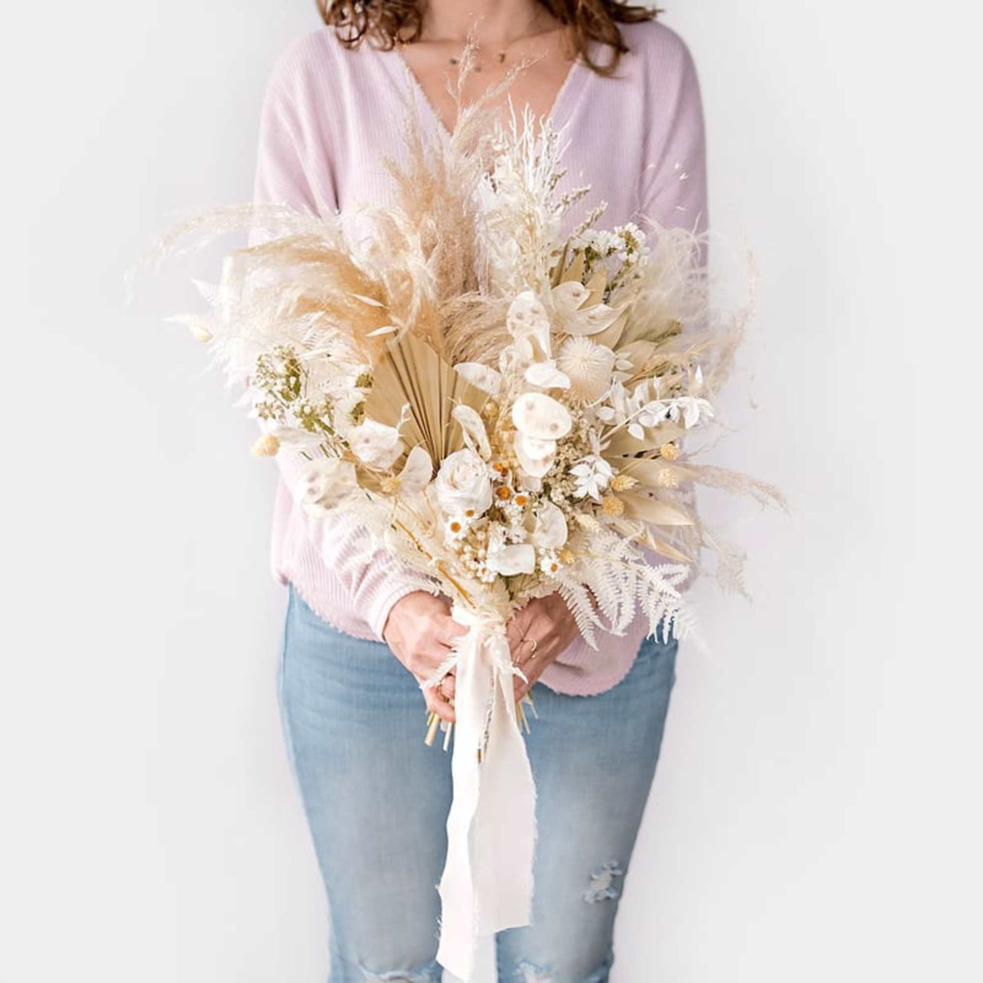 Person holding a large dried bouquet in cream and beige tones