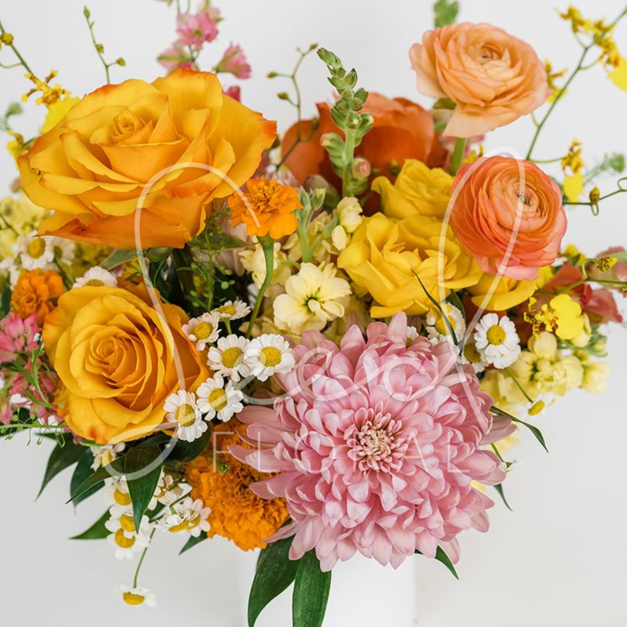 Bright arrangement of yellow roses, peach ranunculus and pink chrysanthemum in a white vase